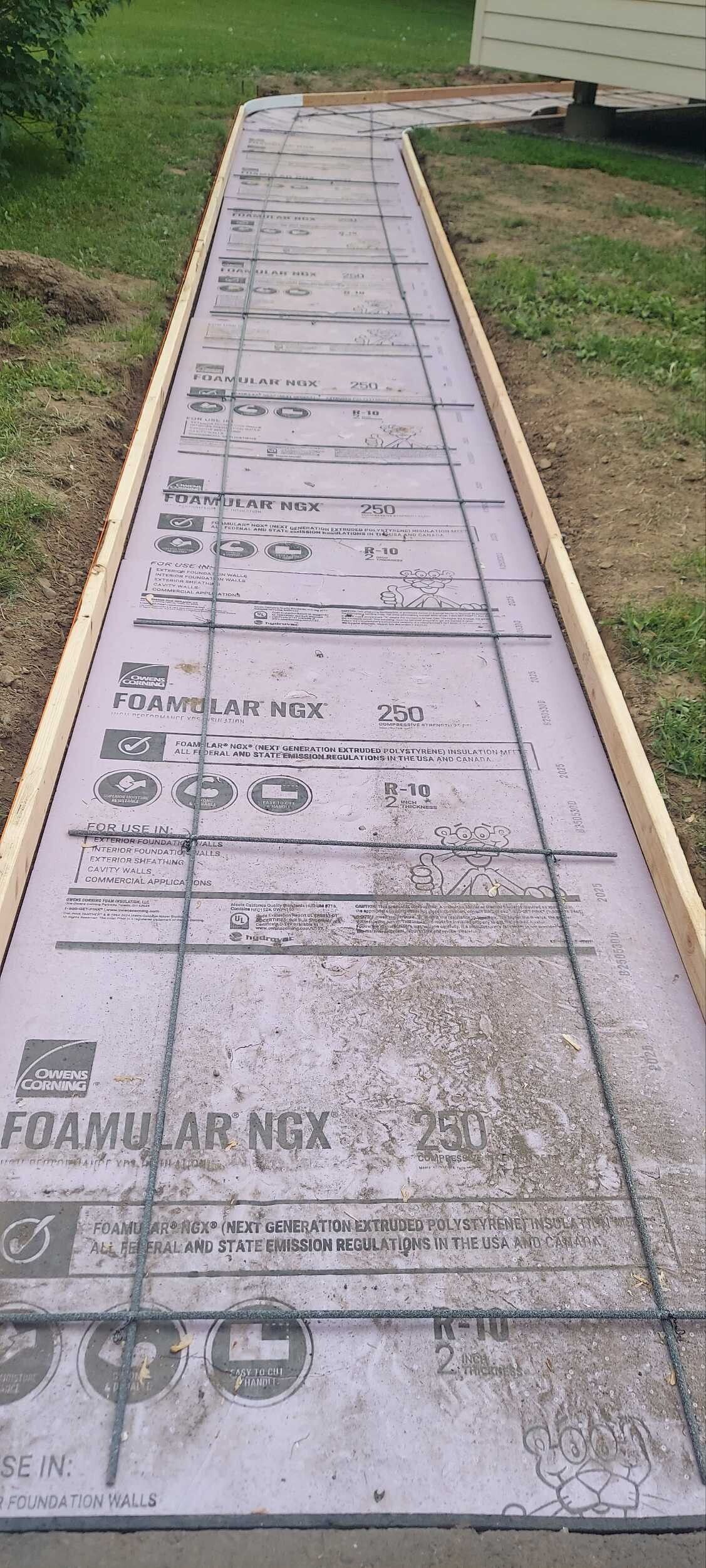 A long concrete walkway is being built in a yard.