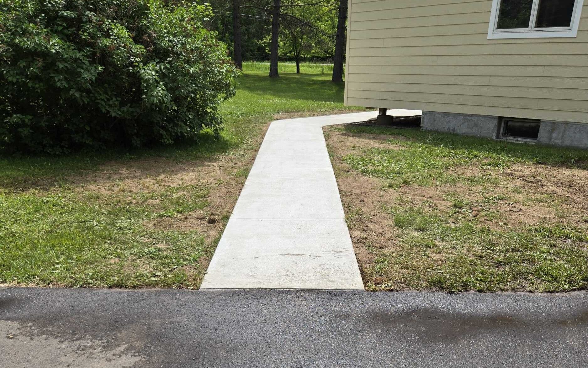 A concrete walkway leading to a house in the grass