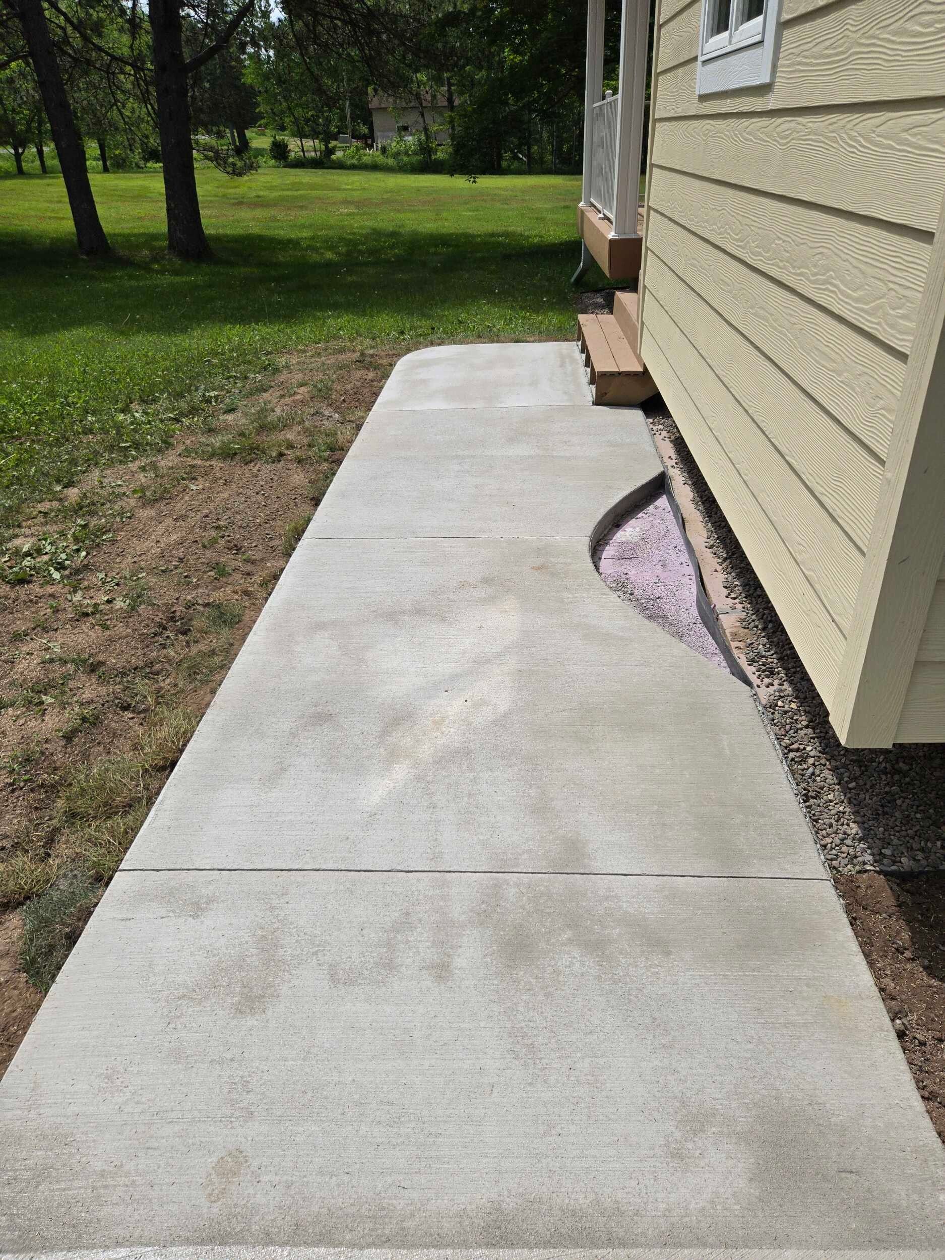 A concrete walkway leading to the side of a house.