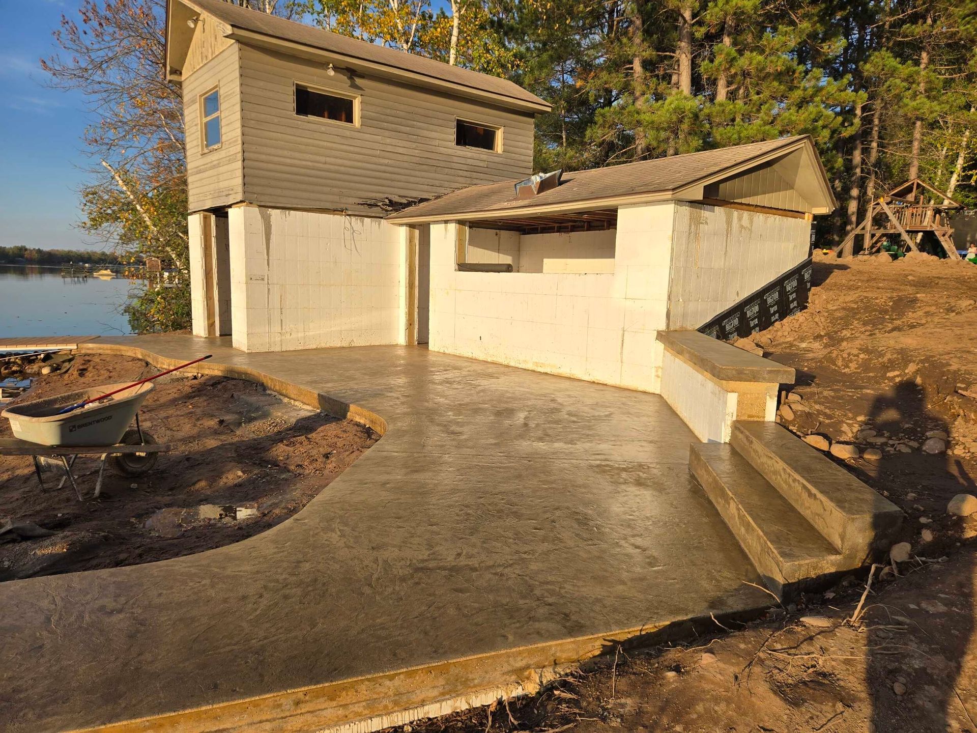 Concrete patio with building; steps, and shoreline.