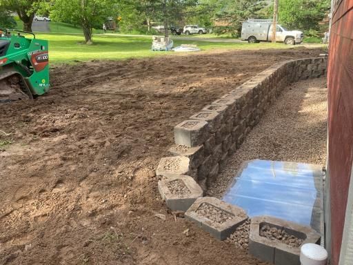 A brick wall is being built in the backyard of a house.