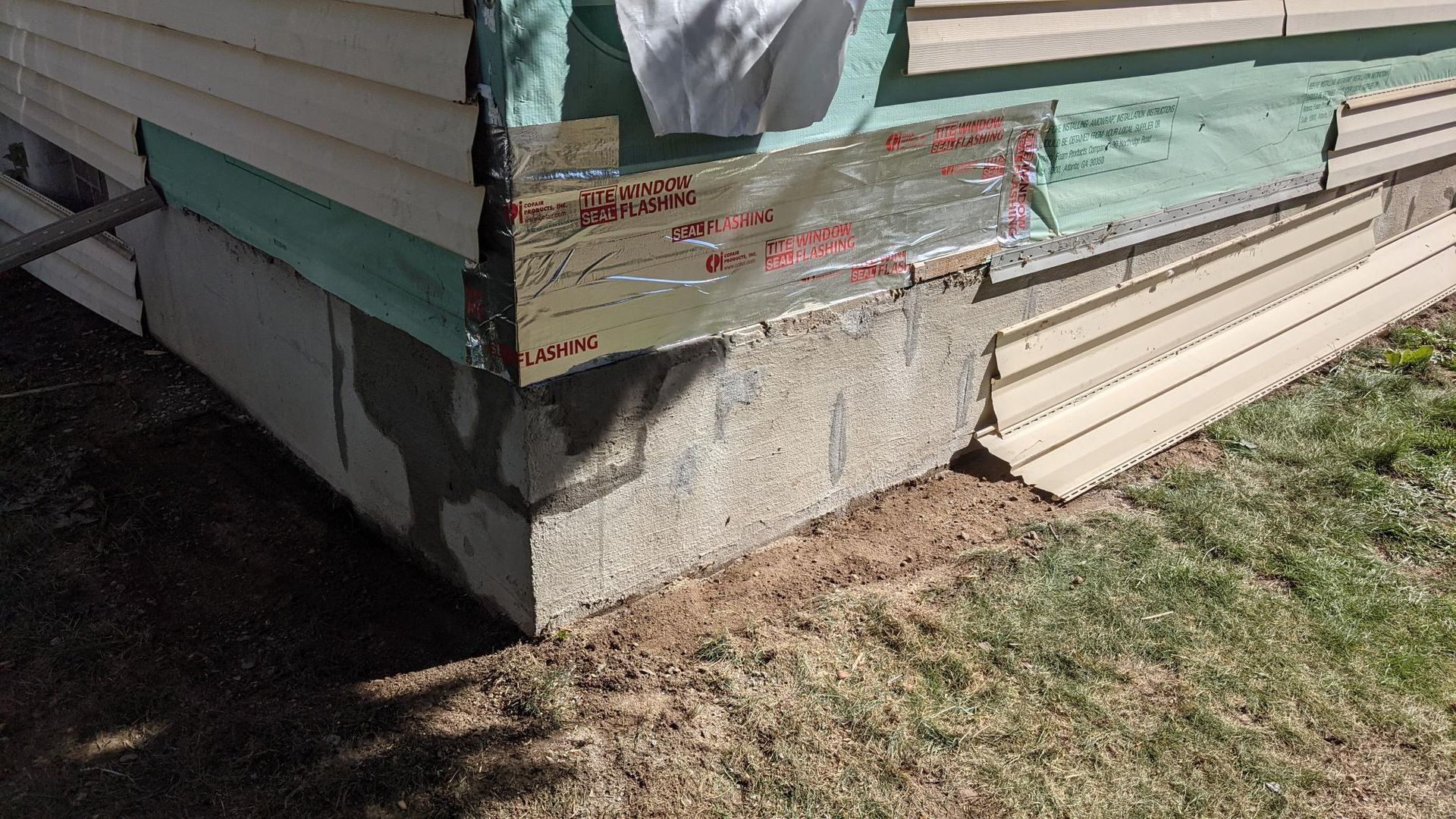 The corner of a house with a concrete foundation is being repaired.