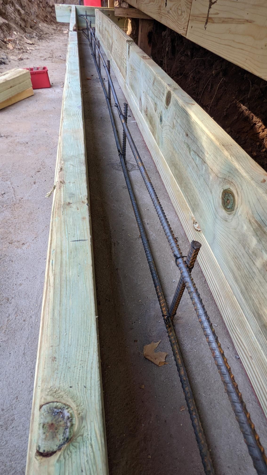 A wooden beam with metal bars attached to it is sitting on the ground.