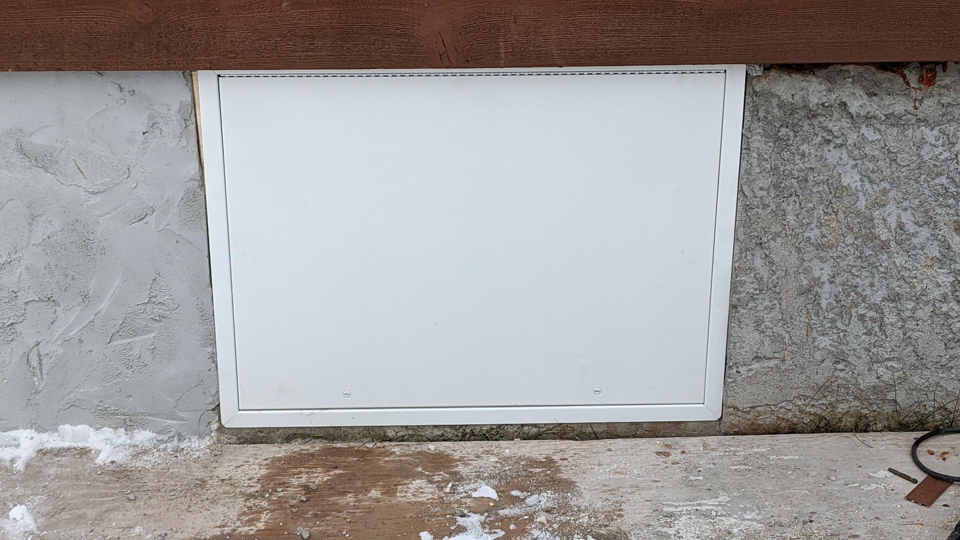A white door is sitting on the ground next to a concrete wall.