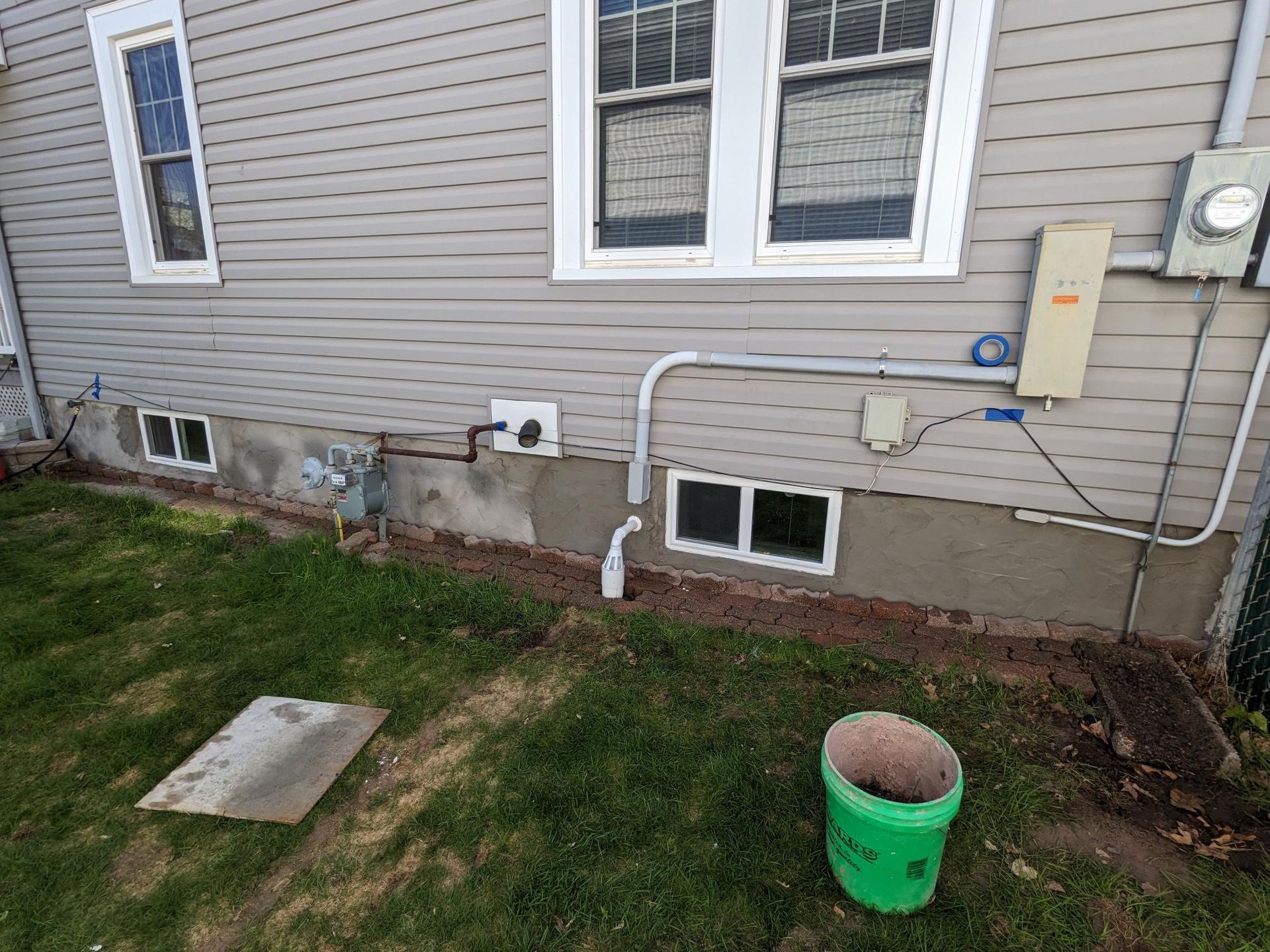A green bucket is sitting in front of a house.