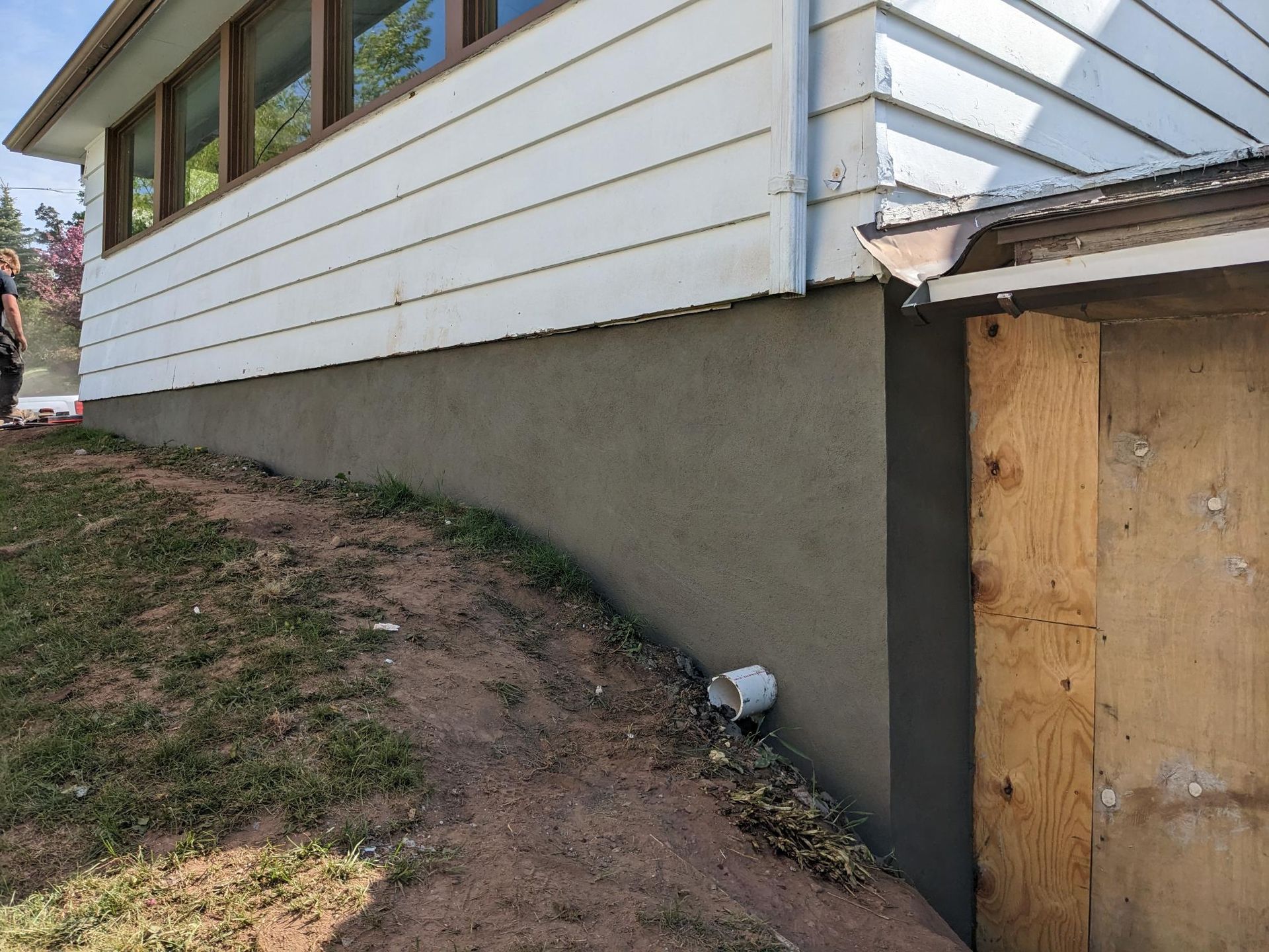 A white house with a wooden shed in front of it.