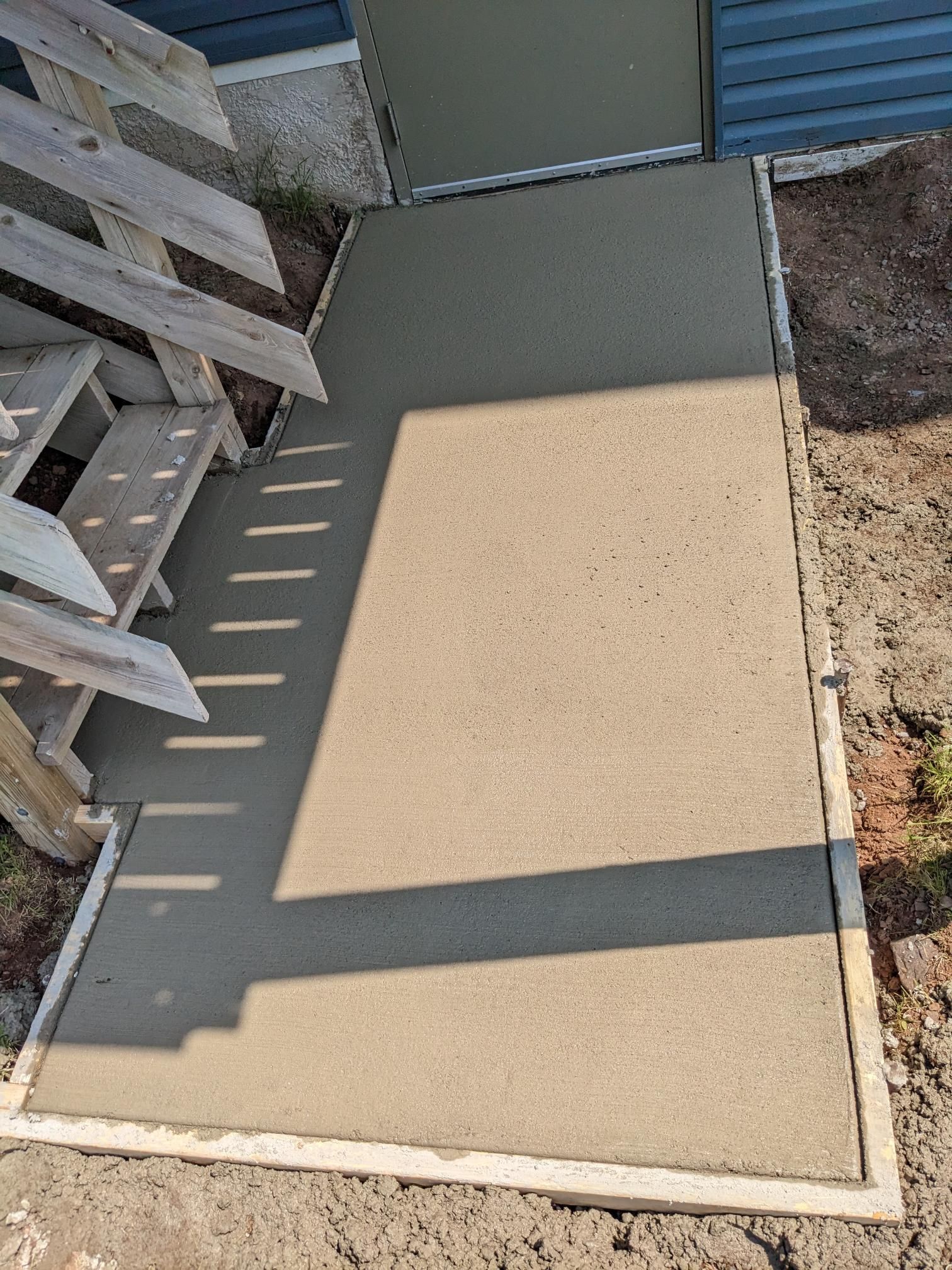 A concrete walkway is being built next to a wooden staircase.