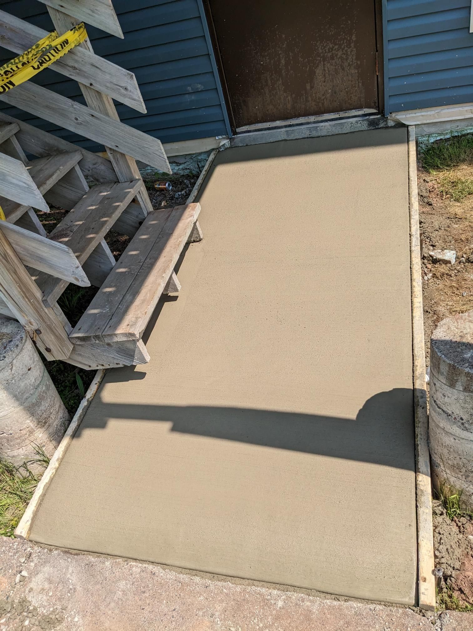 A concrete walkway is being built in front of a house.