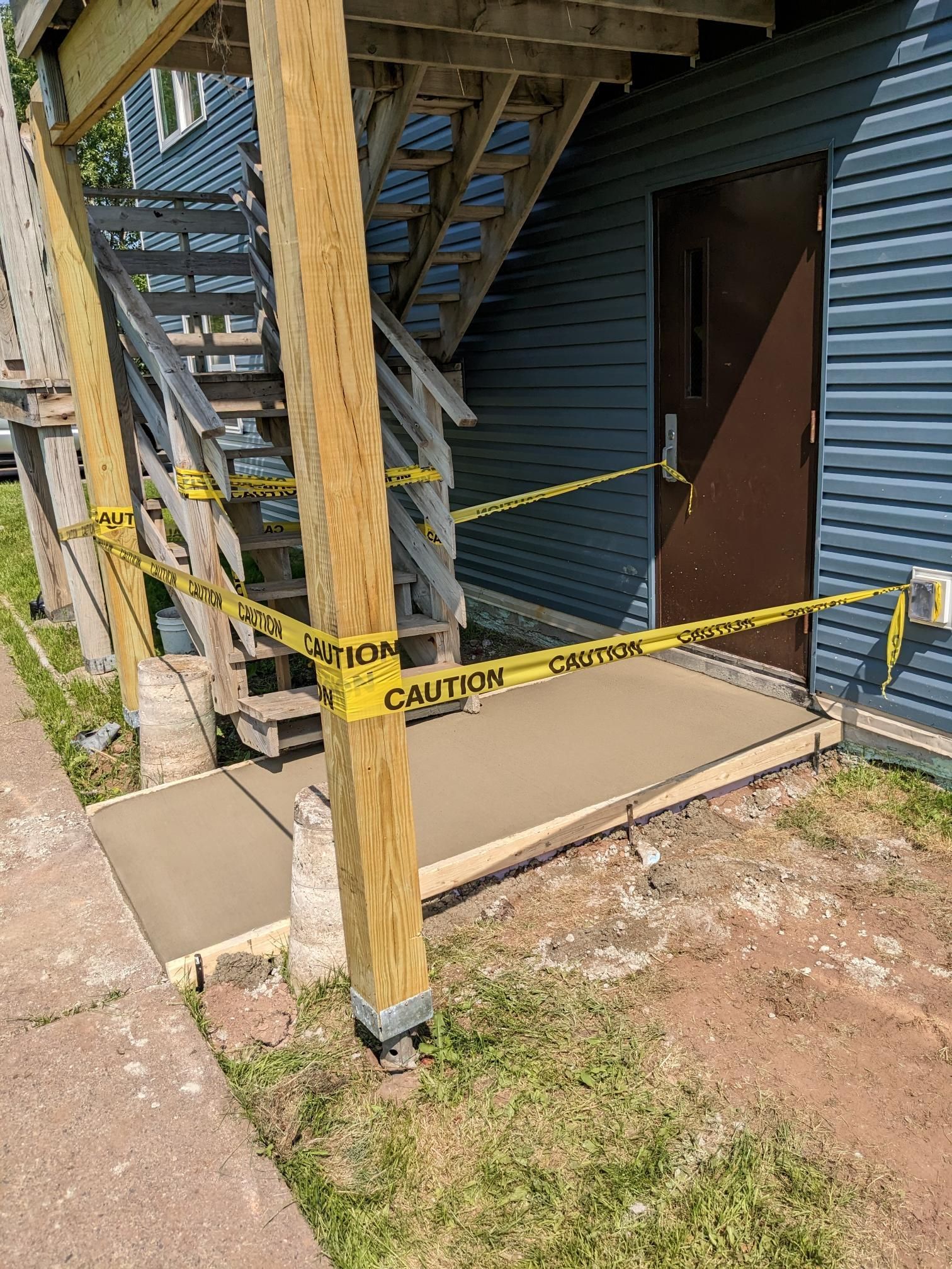 A concrete walkway is being built in front of a building with stairs.