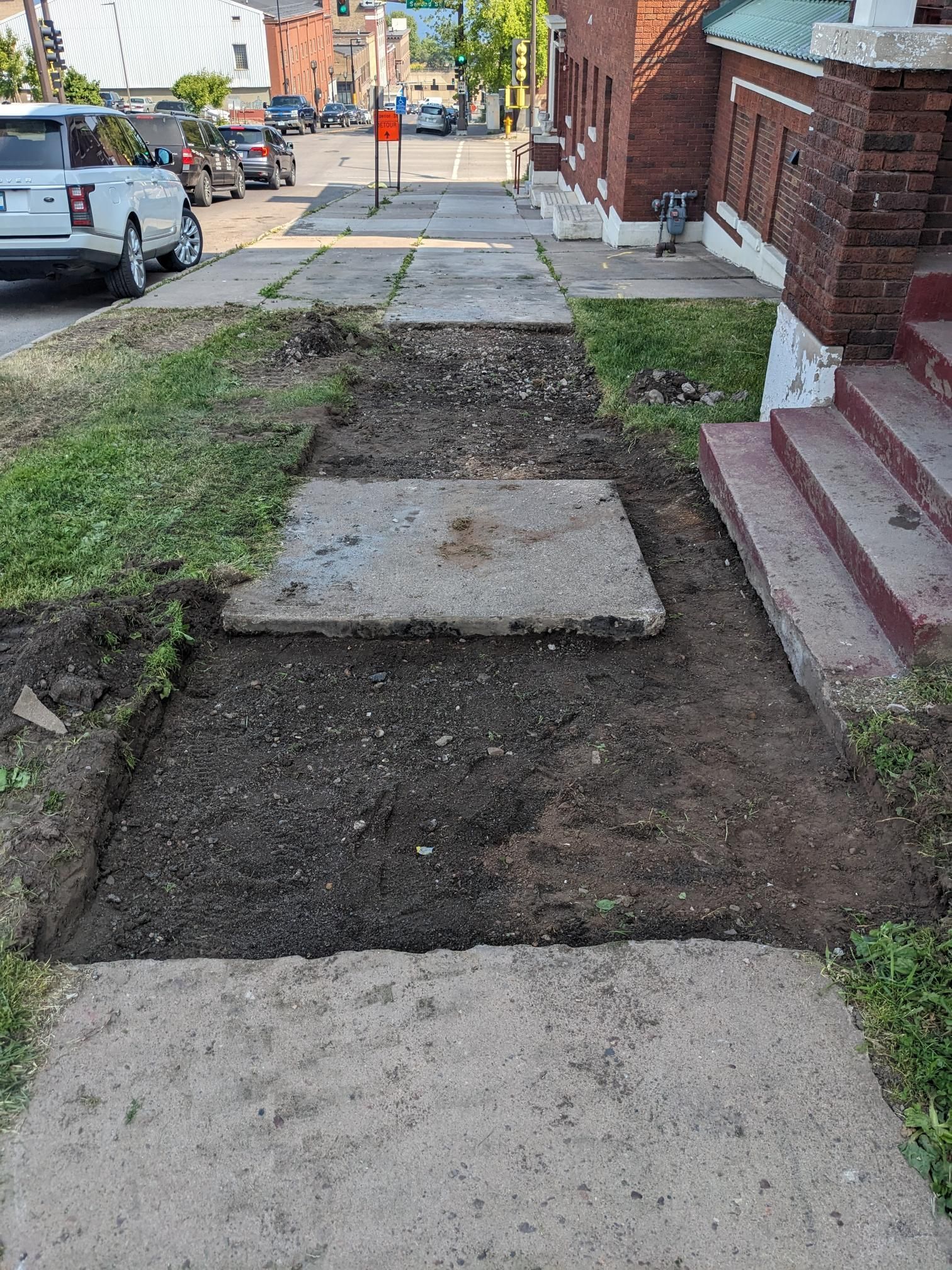 A concrete walkway is being built next to a brick building.