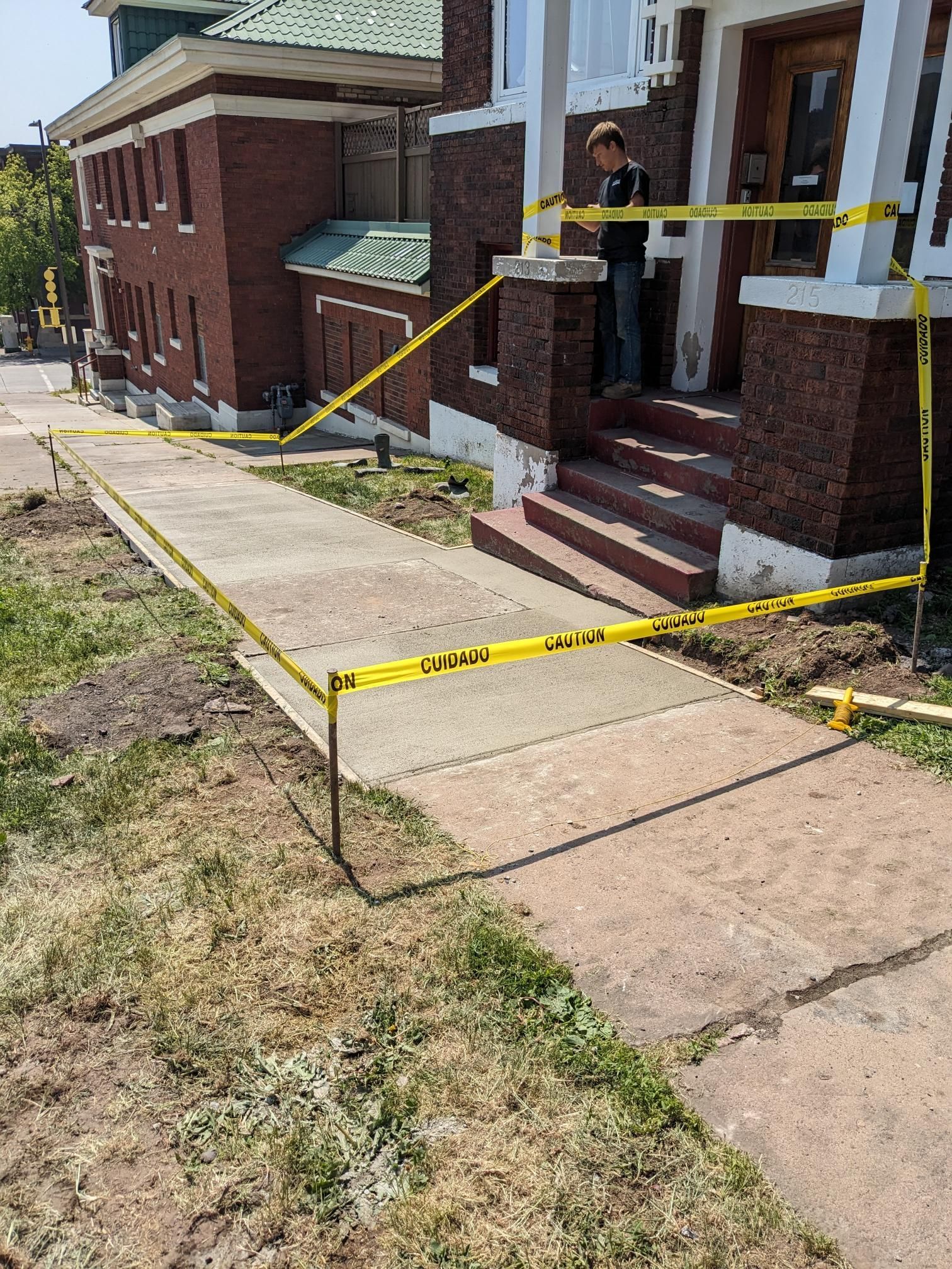 A woman is standing on a sidewalk in front of a brick building.