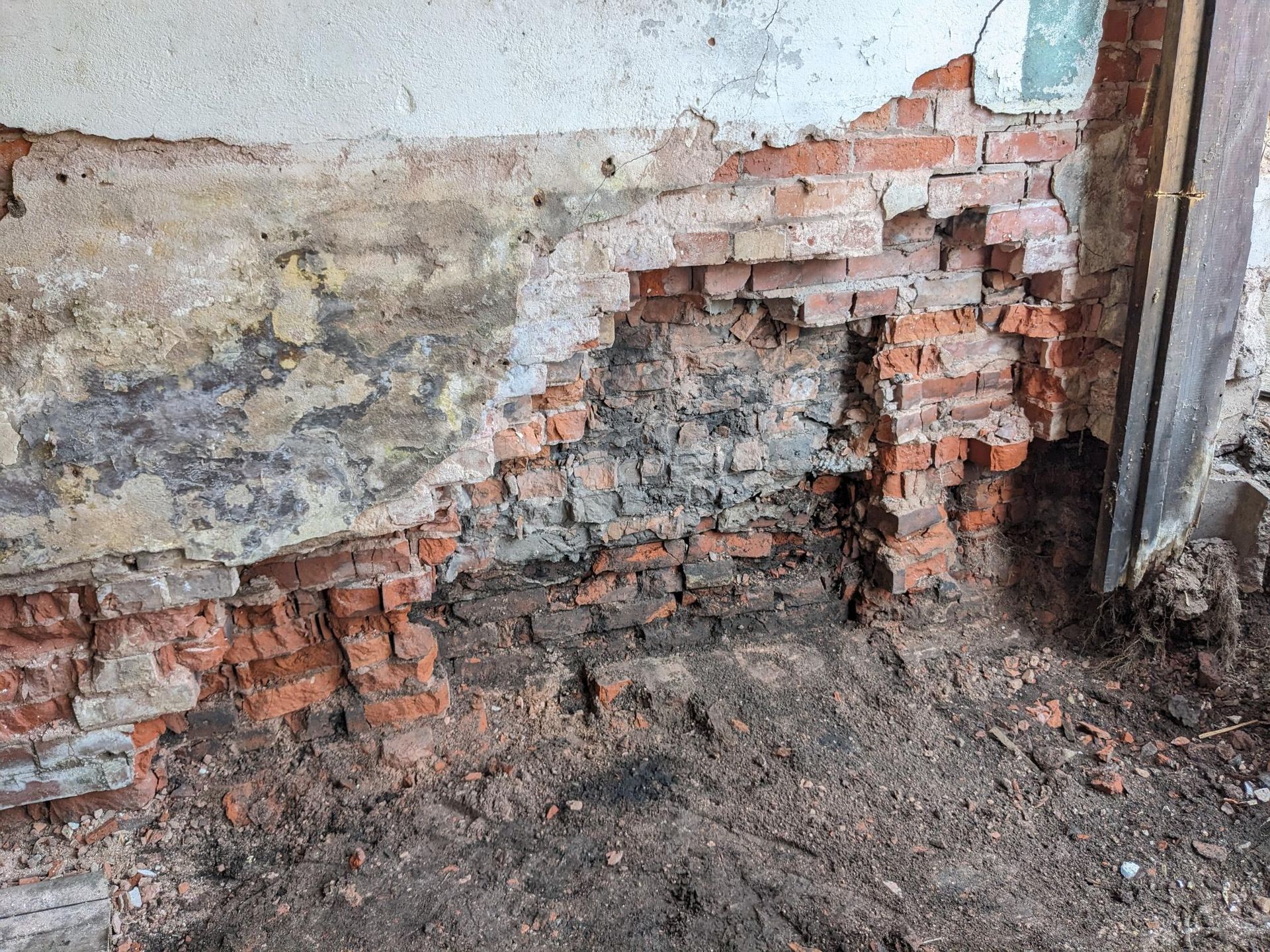 A brick wall with a hole in it and a hole in the ground.