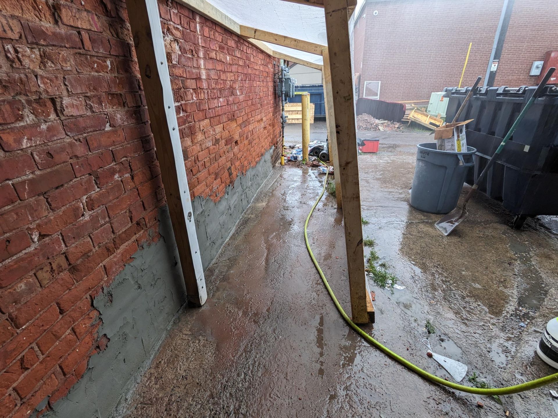 A hose is hanging from the side of a brick wall.