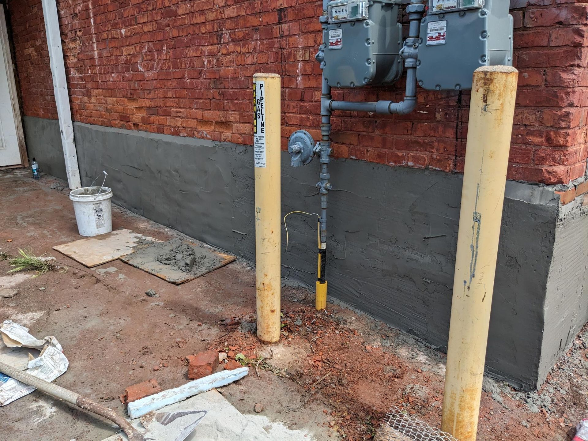 A brick building with a yellow pole in front of it.
