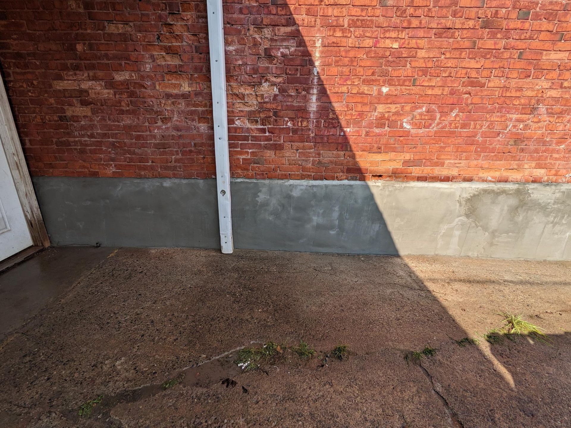 A brick wall with a white pipe on the side of it.