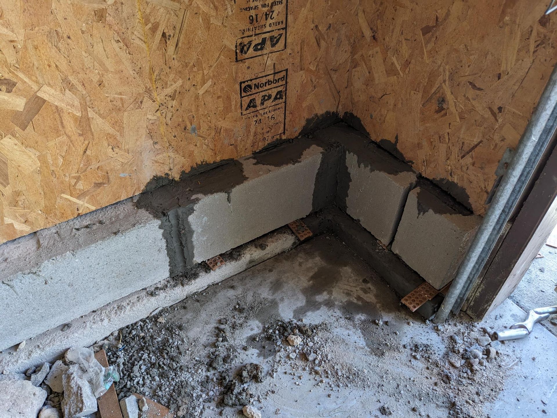 A corner of a wall is being built with concrete blocks.