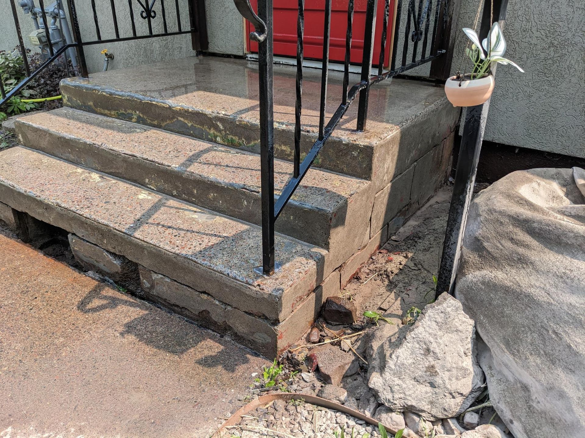 A set of stairs leading up to a house with a wrought iron railing.