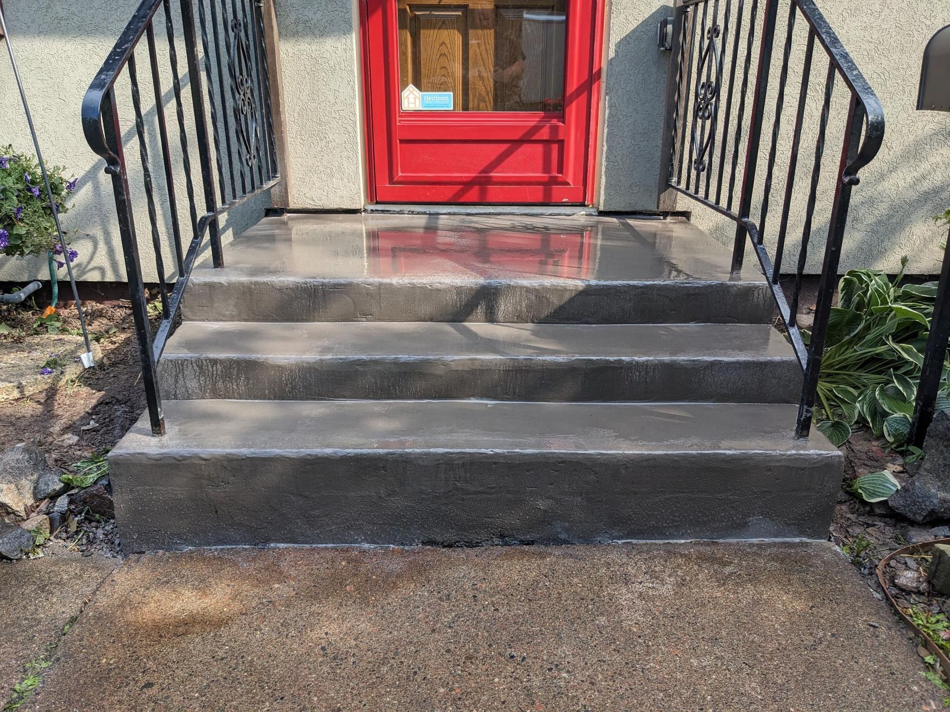 A set of stairs leading up to a red door with a wrought iron railing.