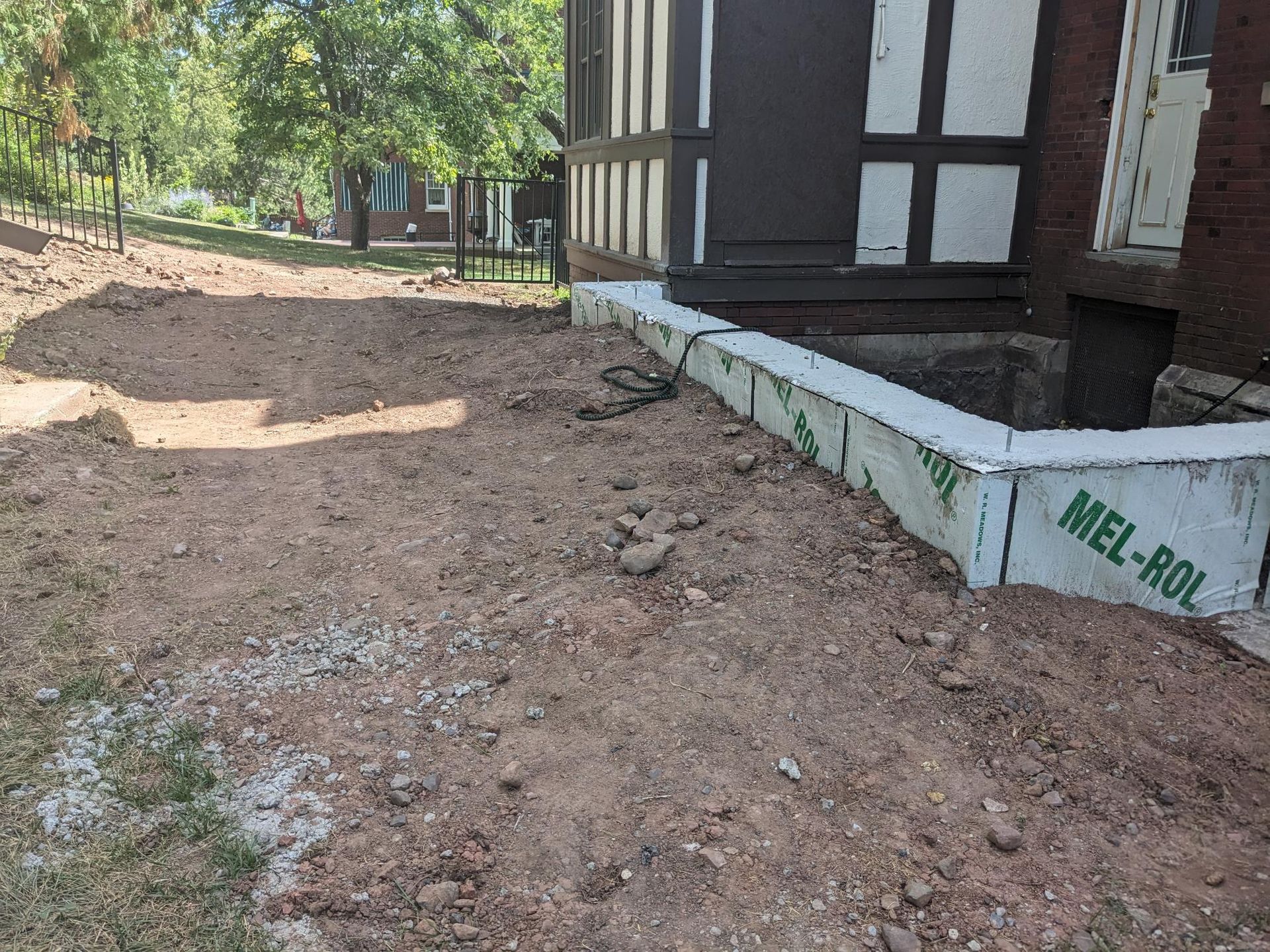 A brick building is being built next to a dirt road.
