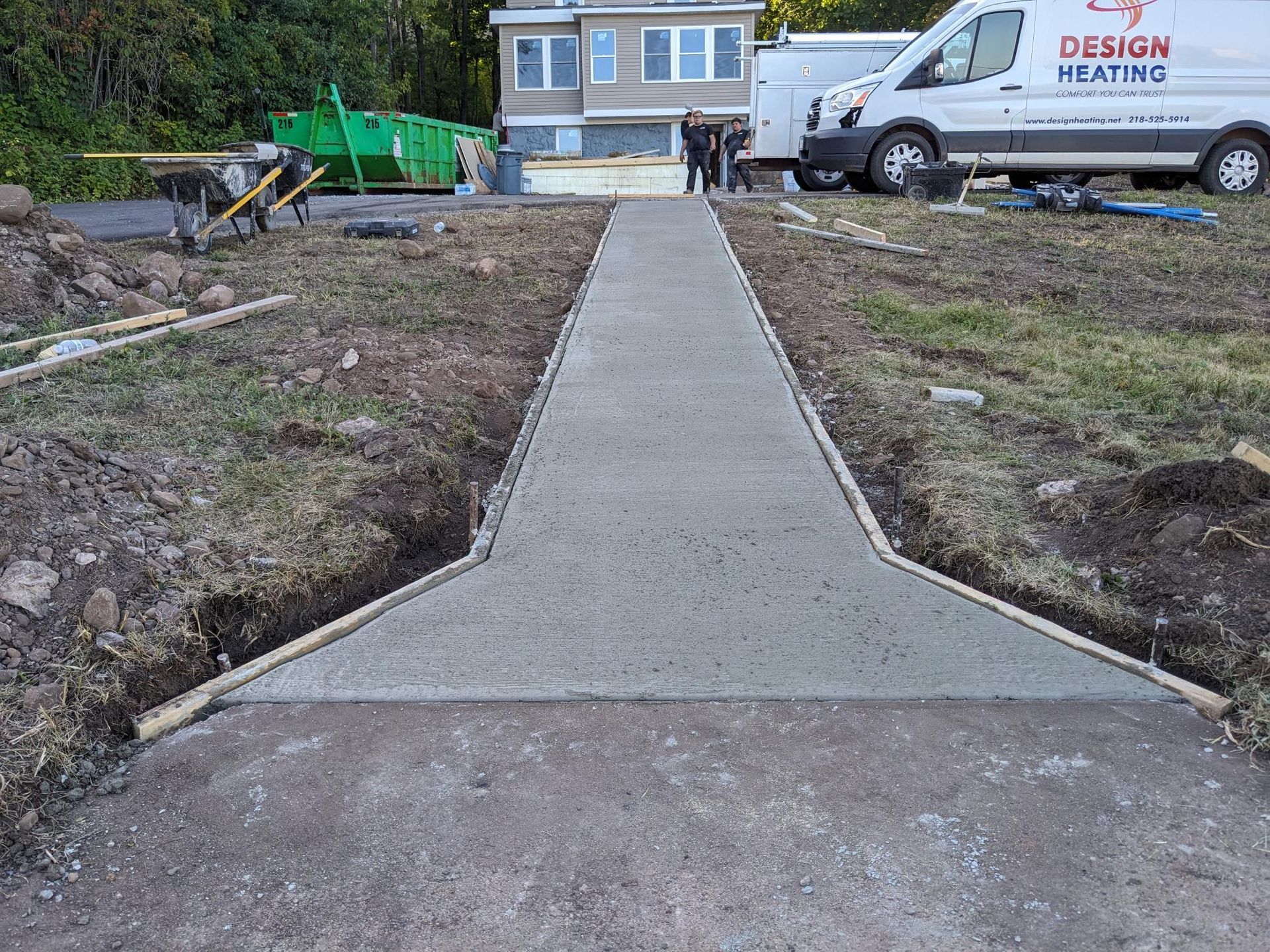 A concrete walkway is being built in front of a house.