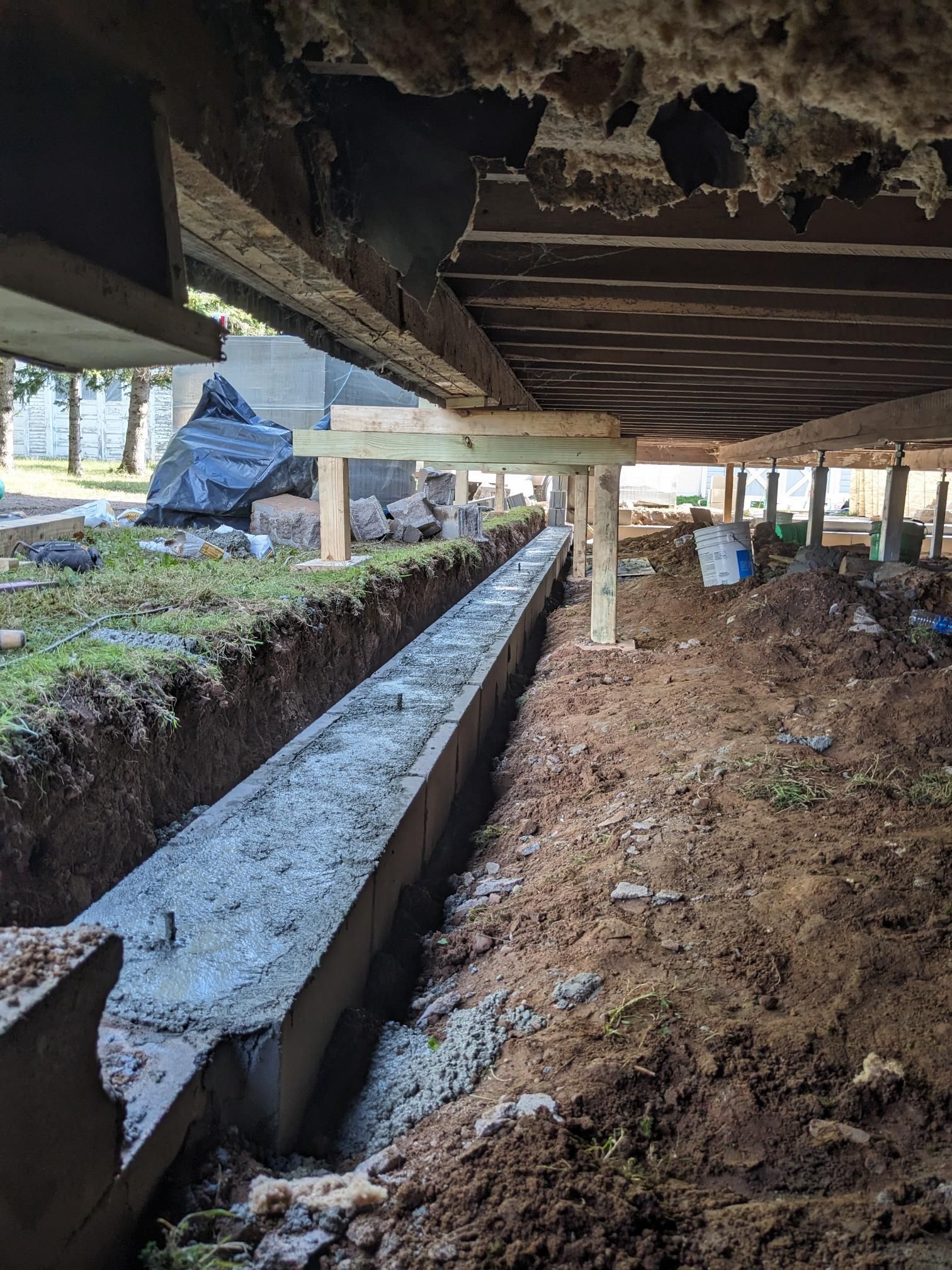 A concrete beam is being installed underneath a wooden deck.