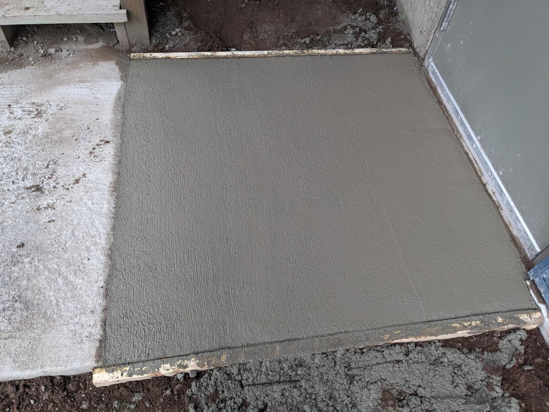 A piece of concrete is sitting on the ground next to a door.
