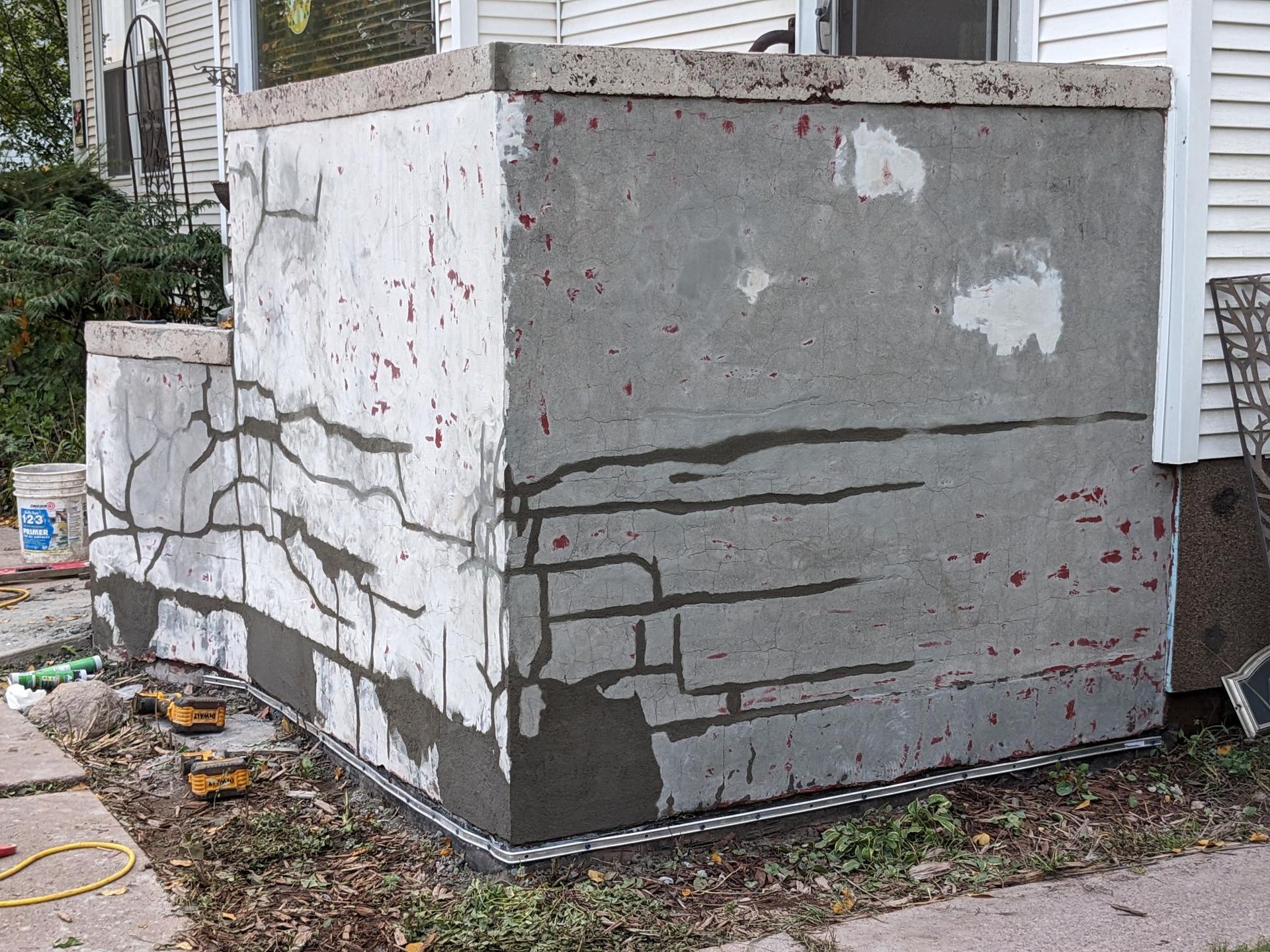 A concrete wall is being repaired on the side of a house.