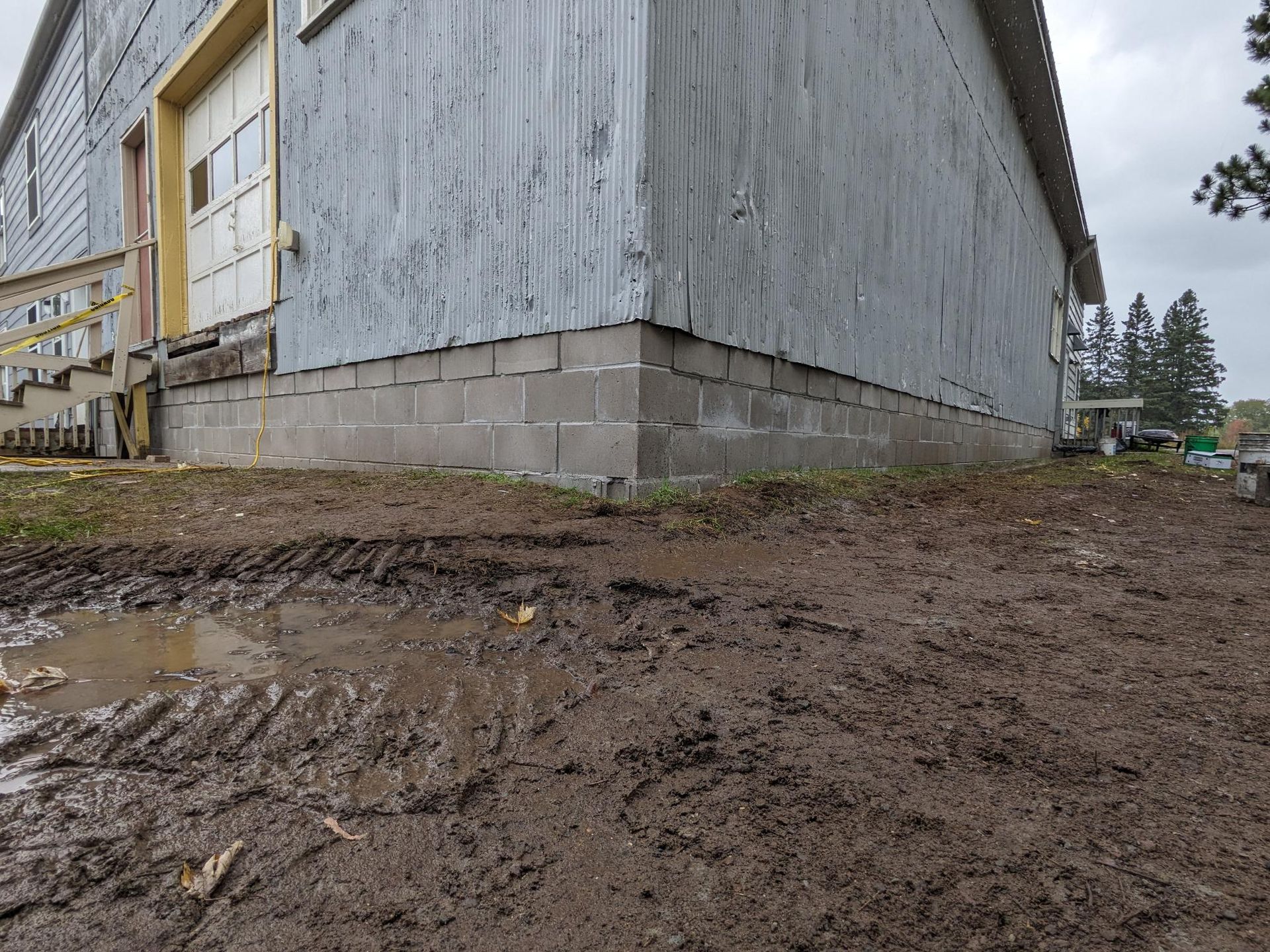 A muddy yard in front of a building with a puddle of water.