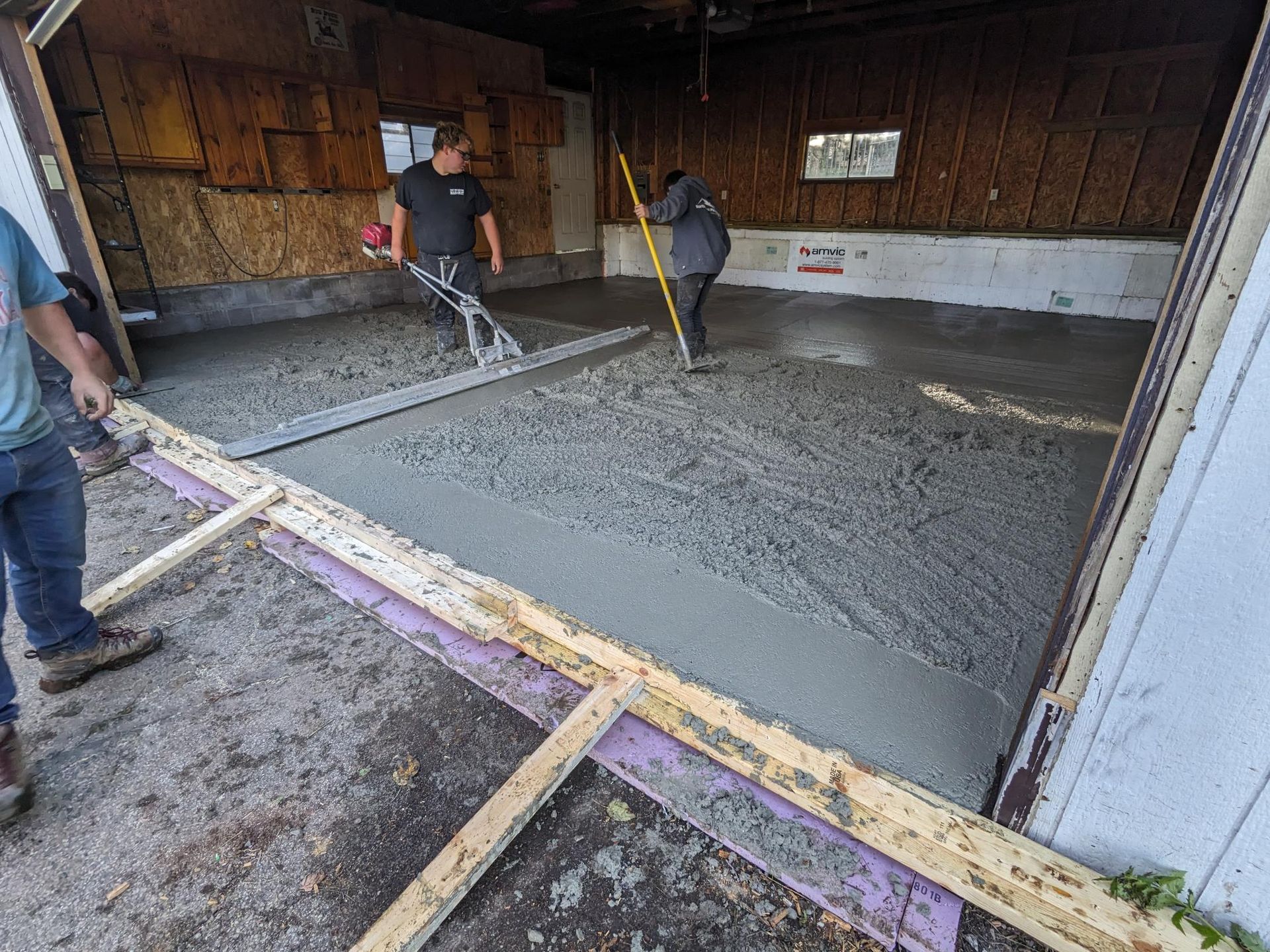 A couple of men are working on a concrete floor in a garage.