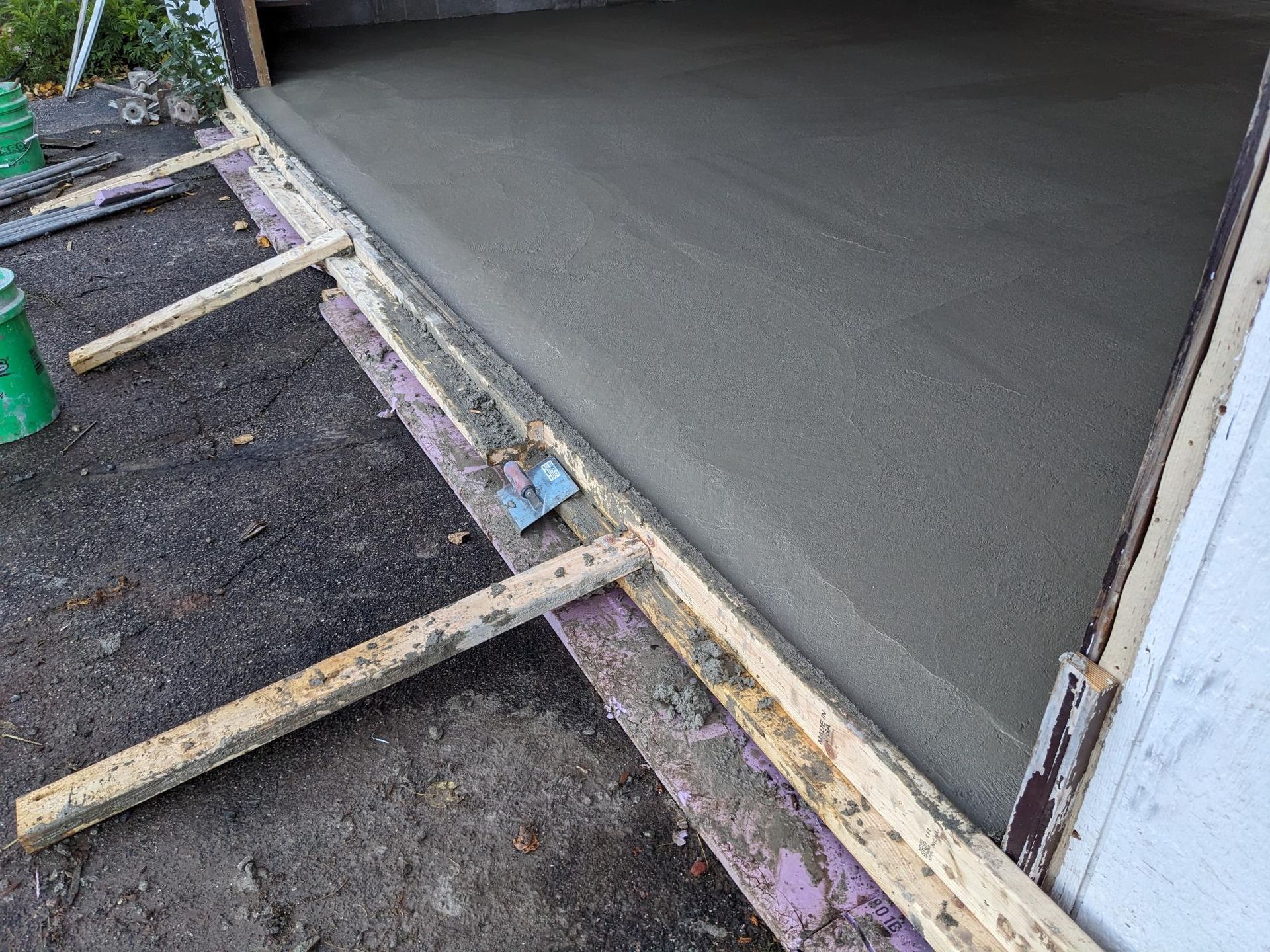 A concrete floor is being poured in front of a garage door.