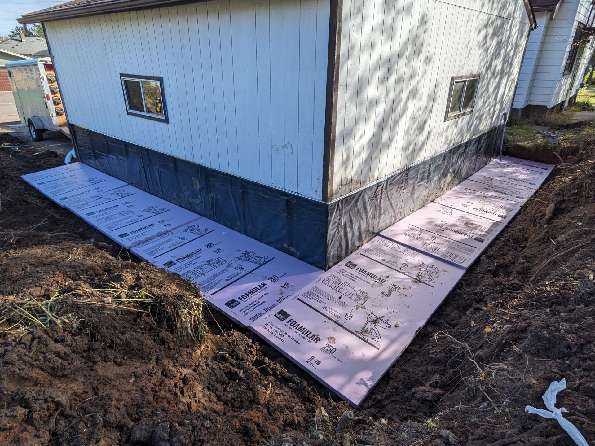The side of a house is being waterproofed with pink foam.