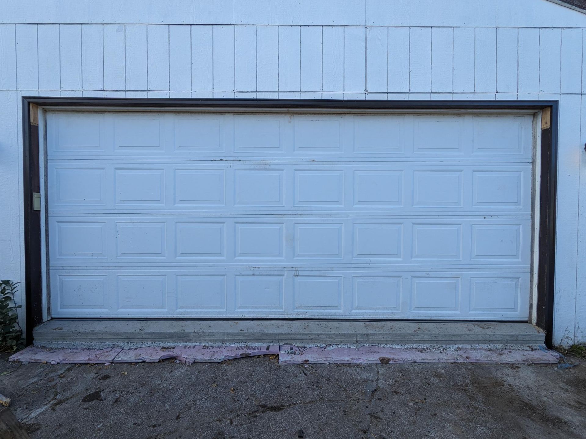 A white garage door is sitting on top of a gravel driveway.