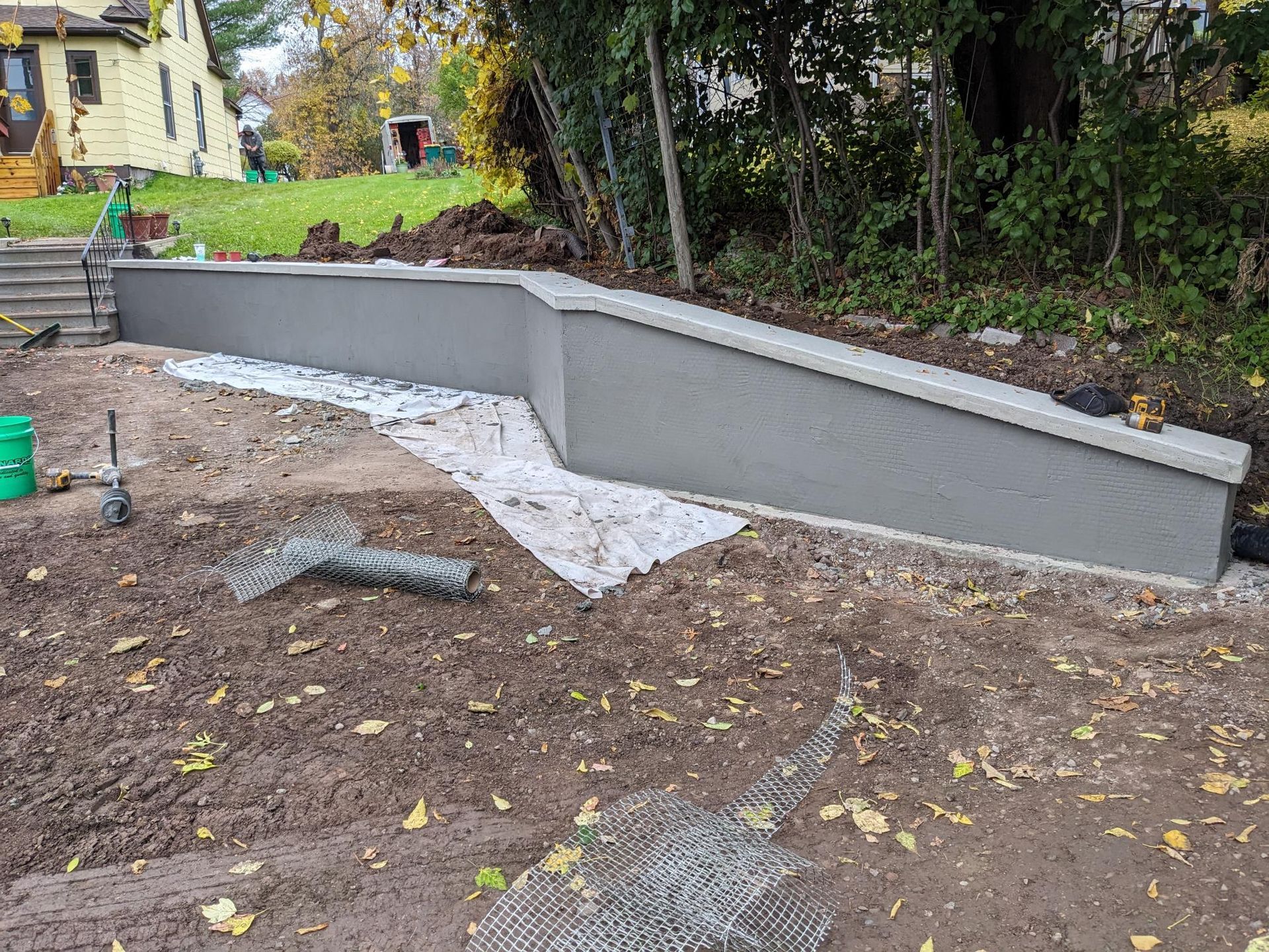 A concrete wall is being built in a yard next to a house.