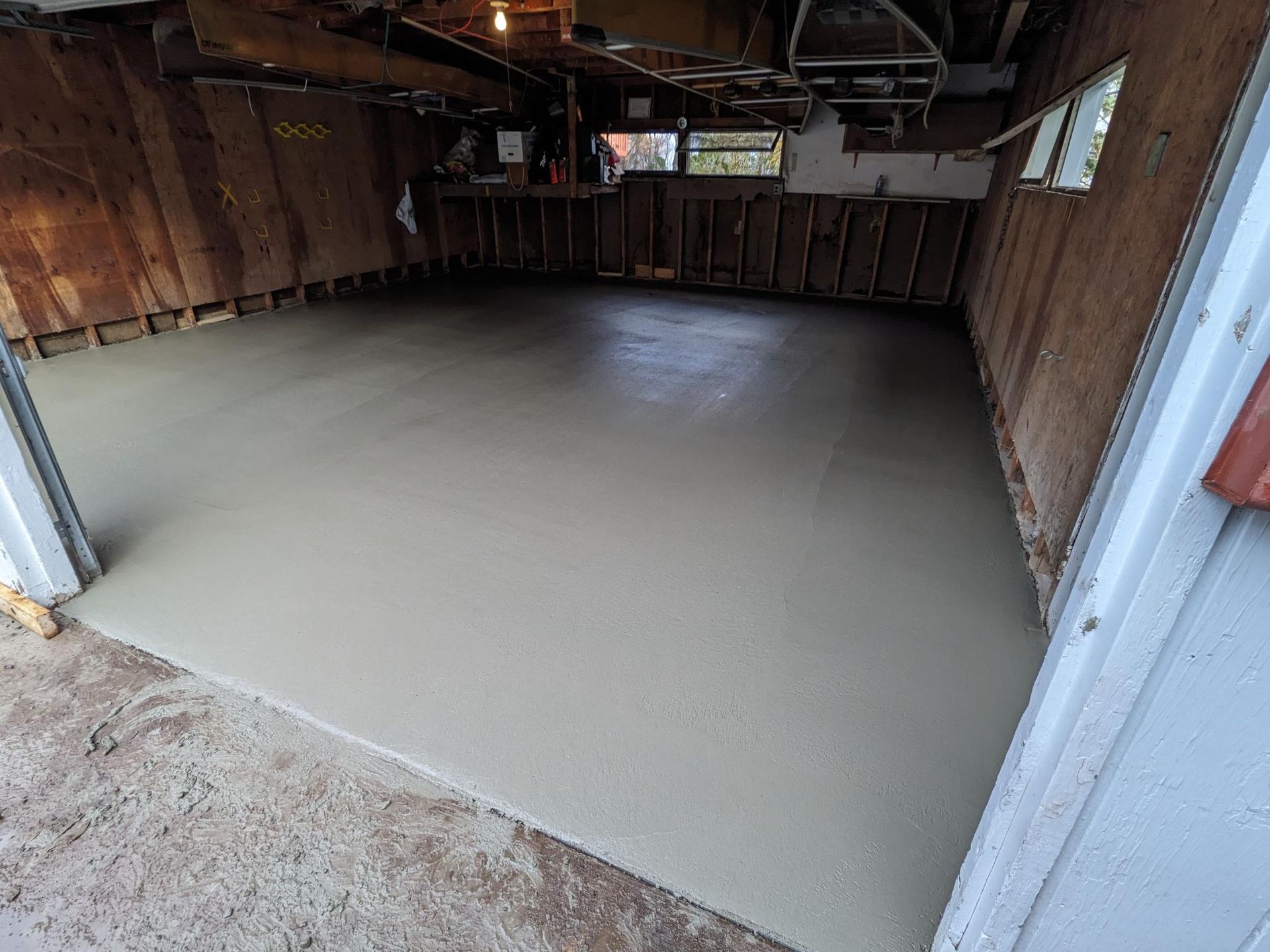 A garage with a concrete floor and a wooden wall.
