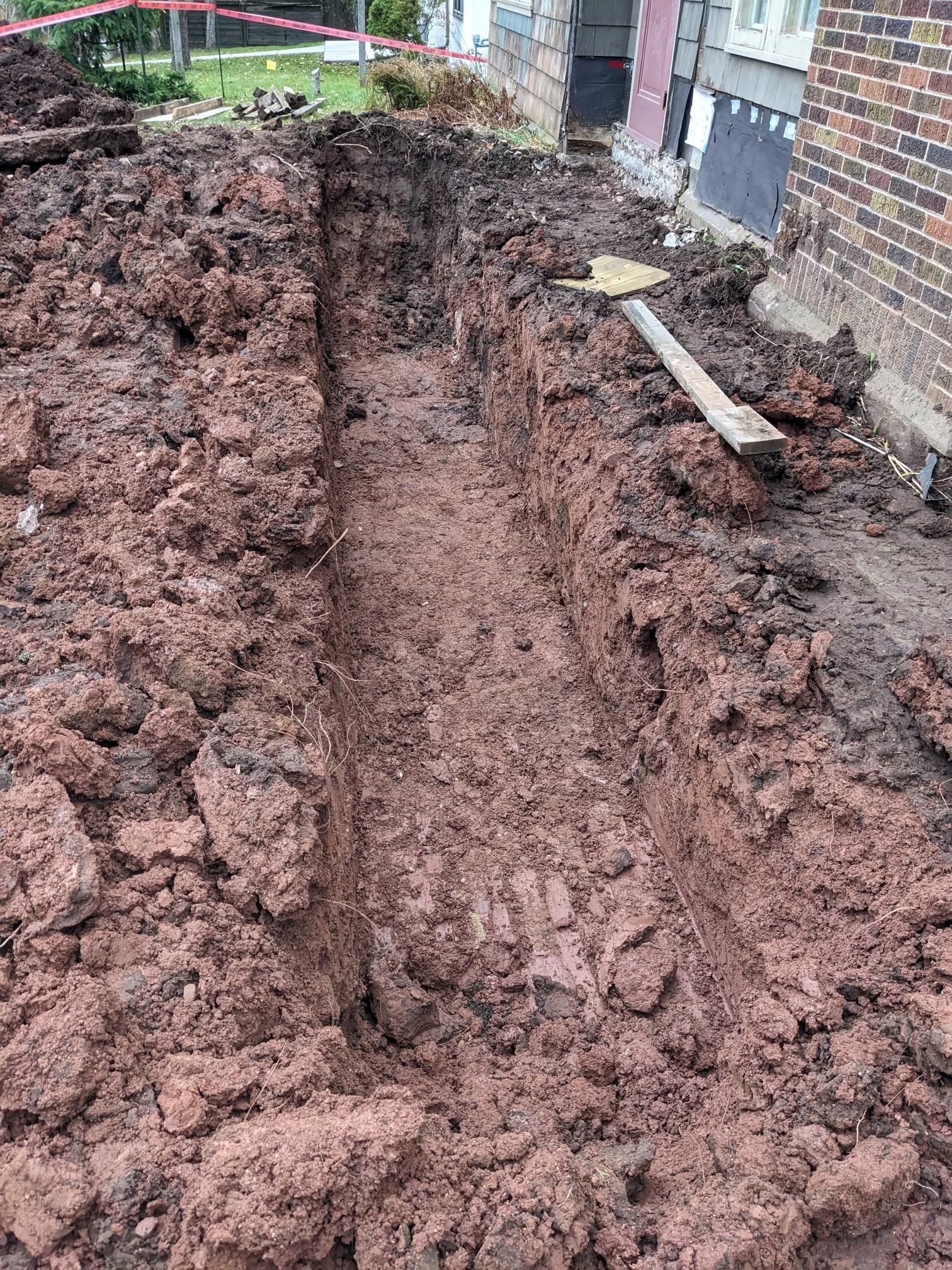 A large pile of dirt is sitting in front of a brick building.