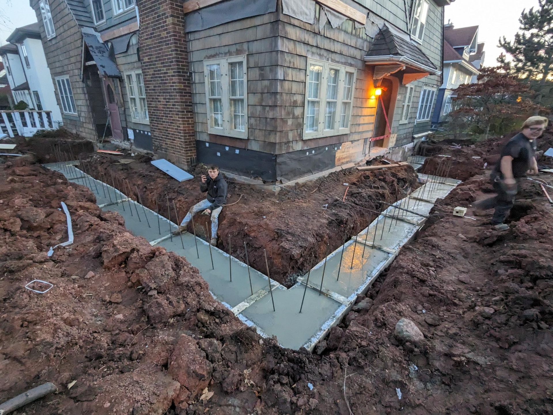 A man is digging a hole in the dirt in front of a house.