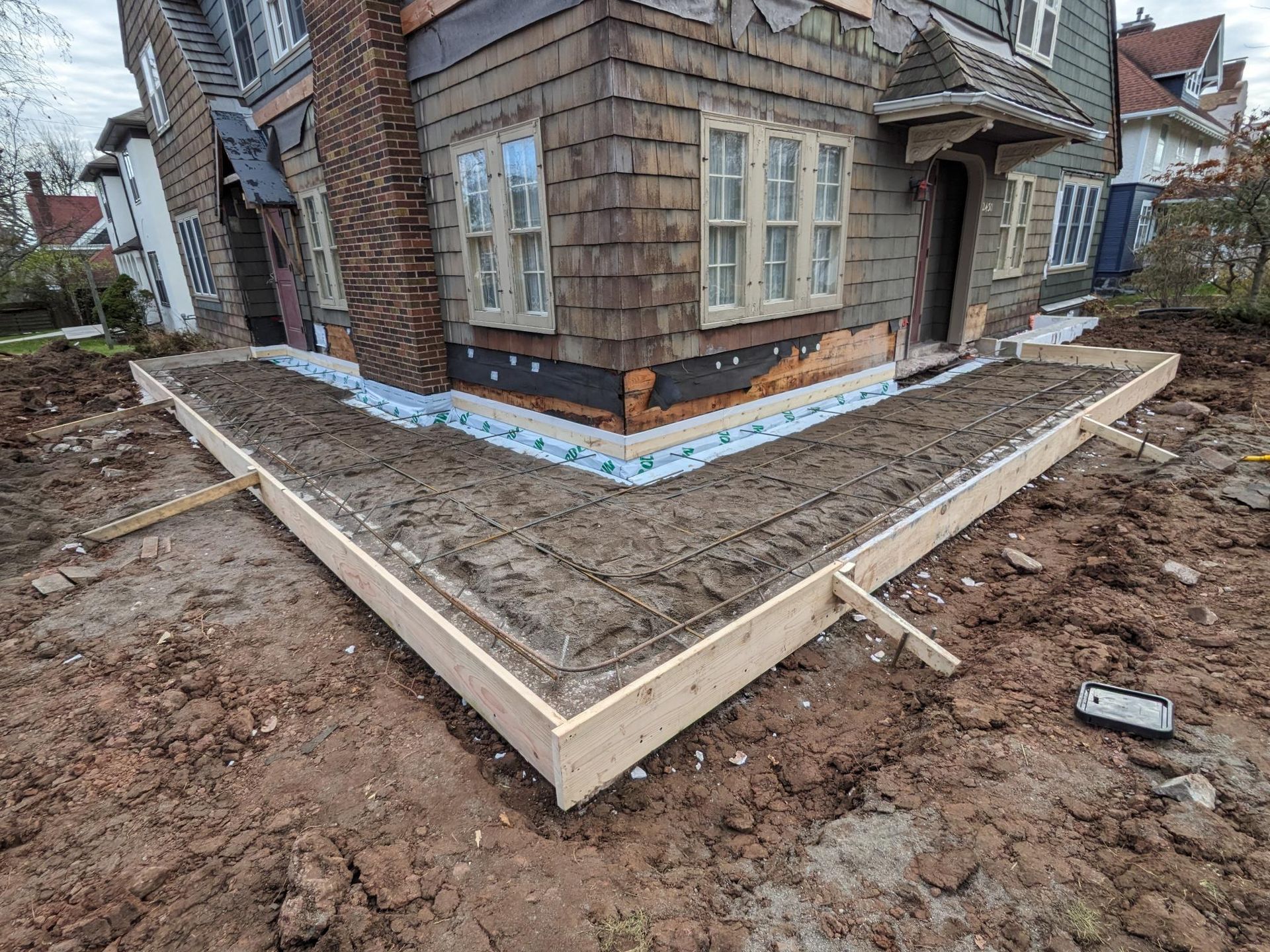 A house is being remodeled and a concrete foundation is being built in front of it.