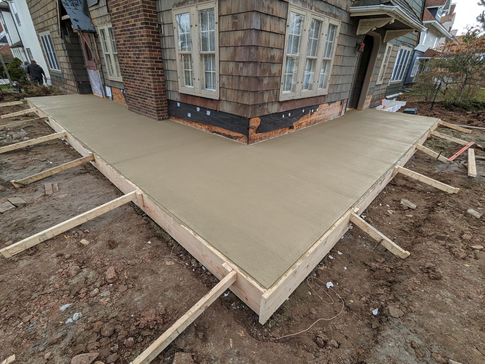 A concrete walkway is being built in front of a house.