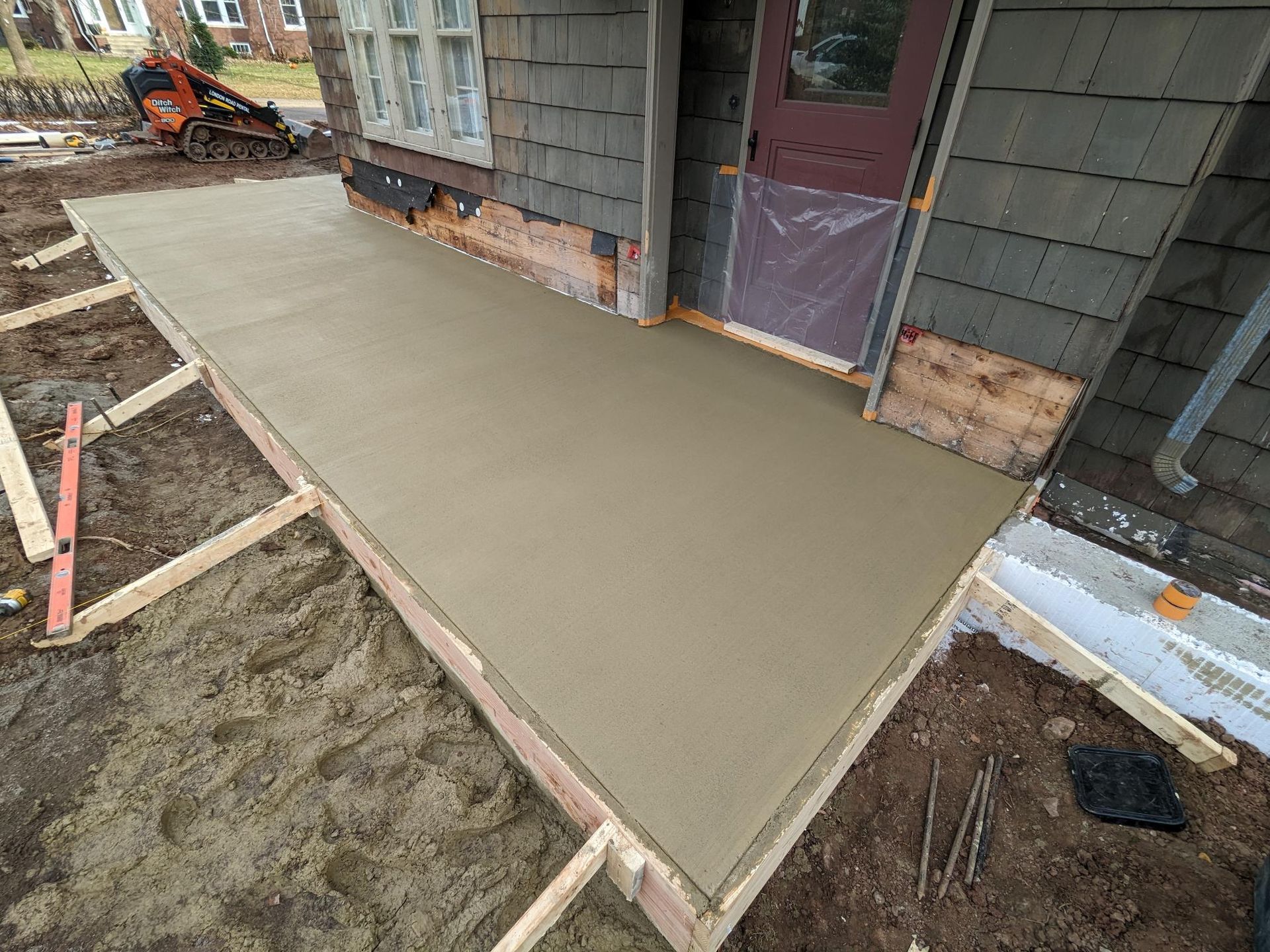 A concrete walkway is being built in front of a house.