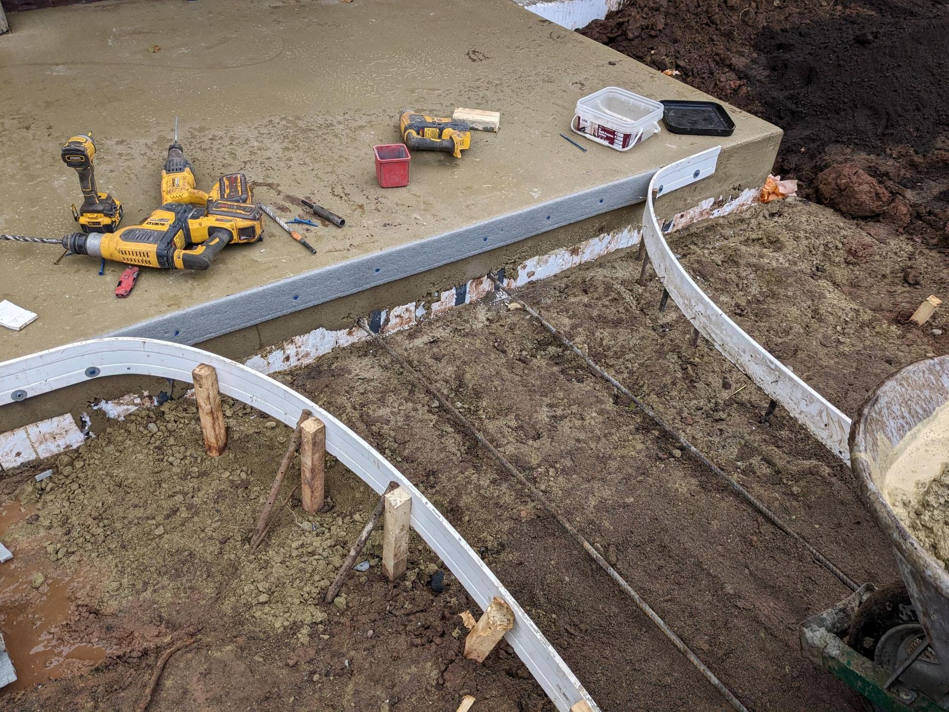 A concrete walkway is being built with tools on the ground.