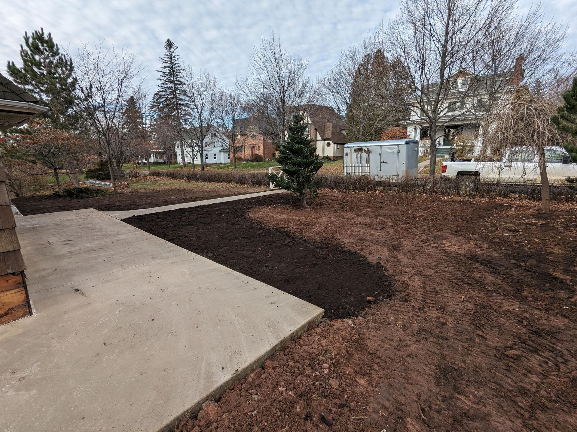 A dirt yard with a concrete walkway leading to a house.