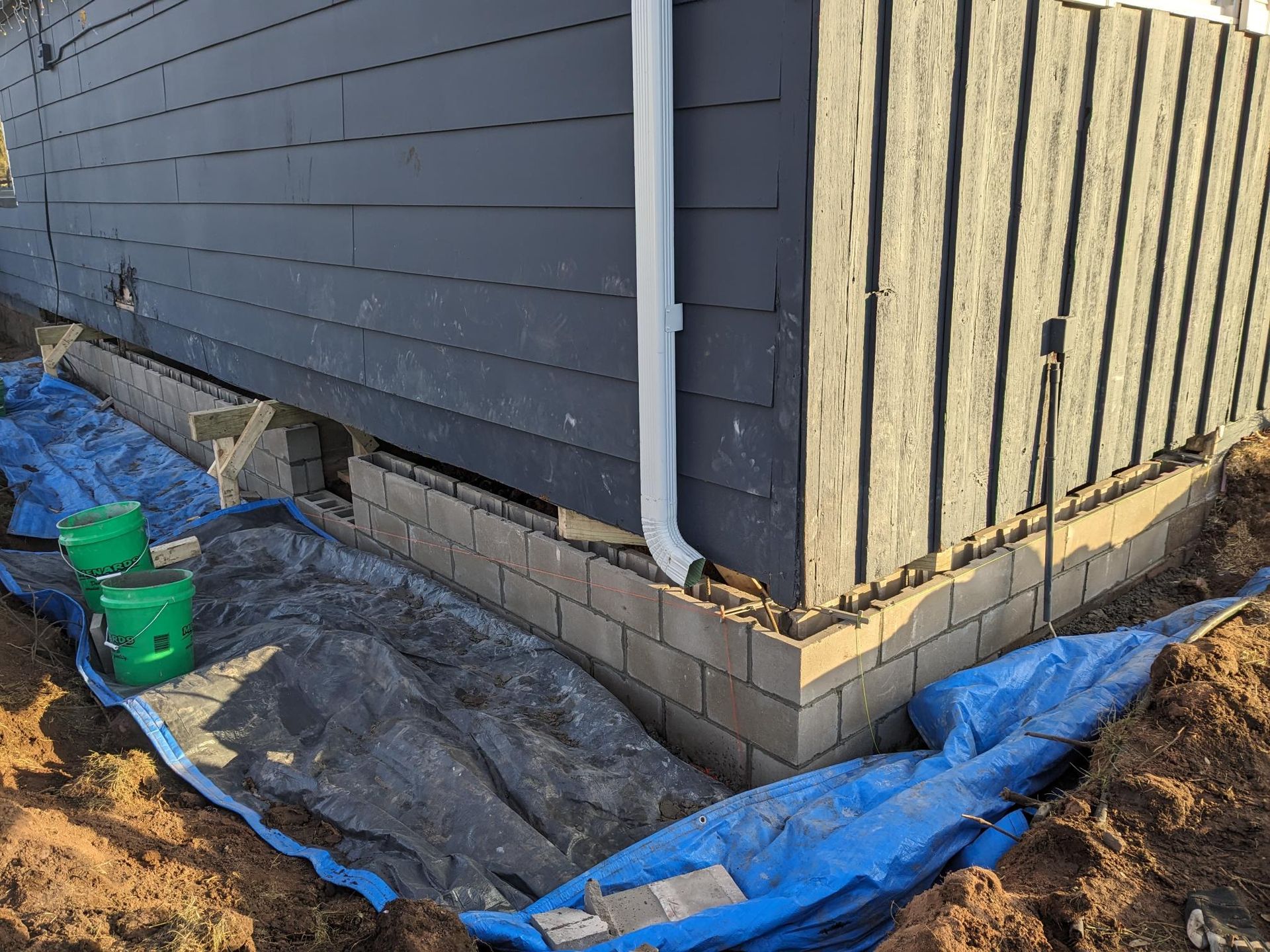 A blue tarp is covering the corner of a house.