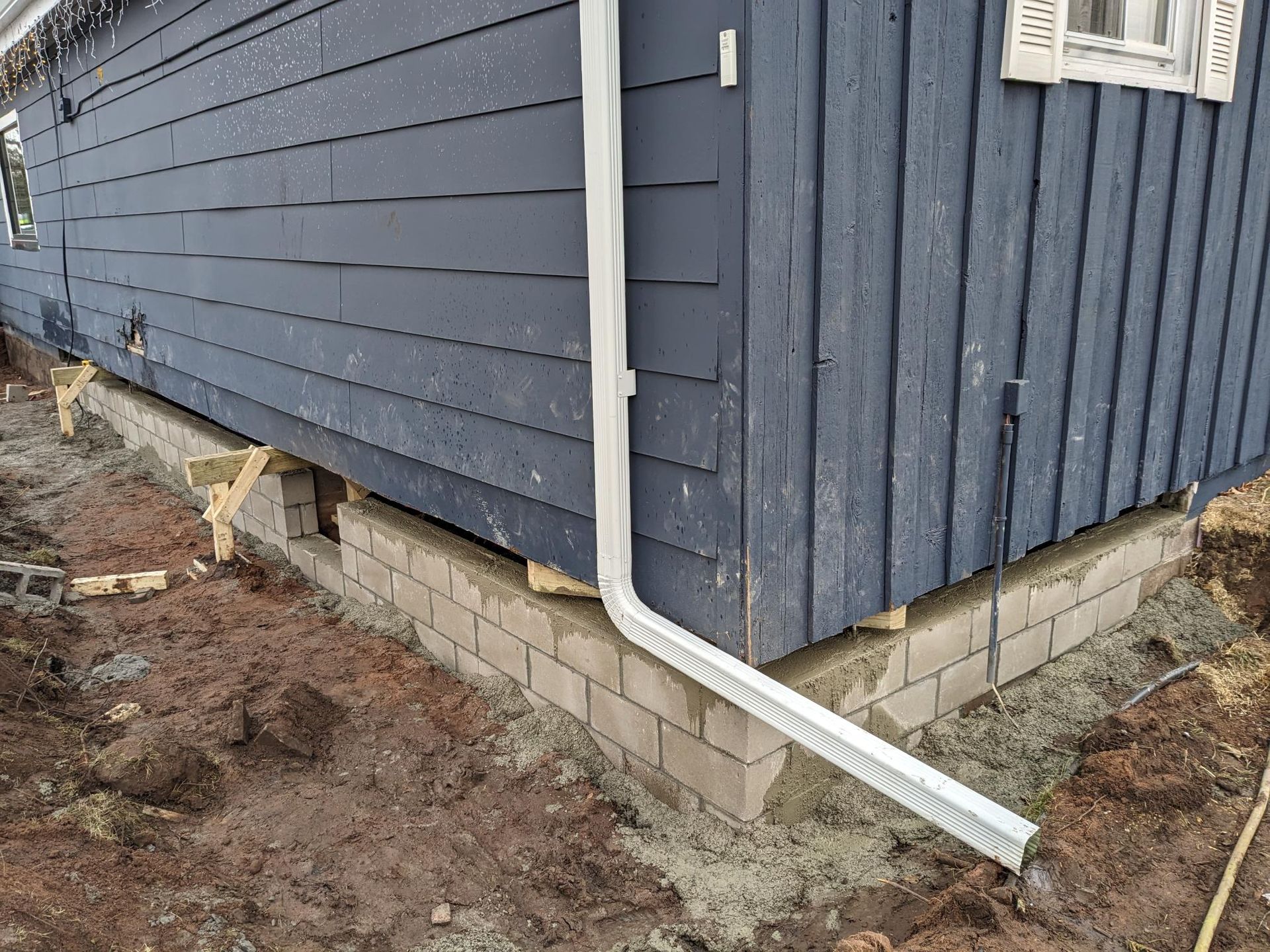 A blue house with a white gutter on the side of it.