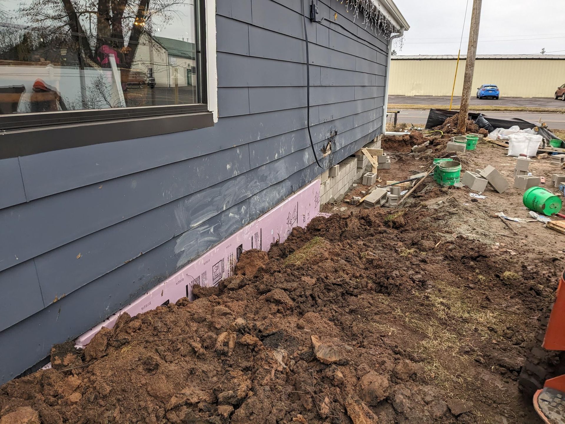 A house is being remodeled and a pile of dirt is in front of it.