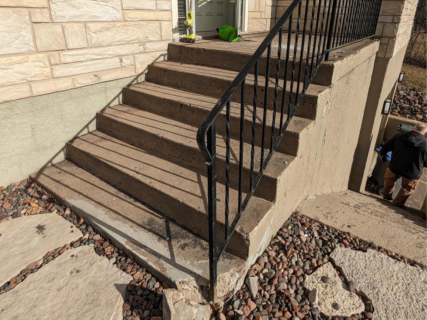 A set of stairs leading up to a house with a metal railing.