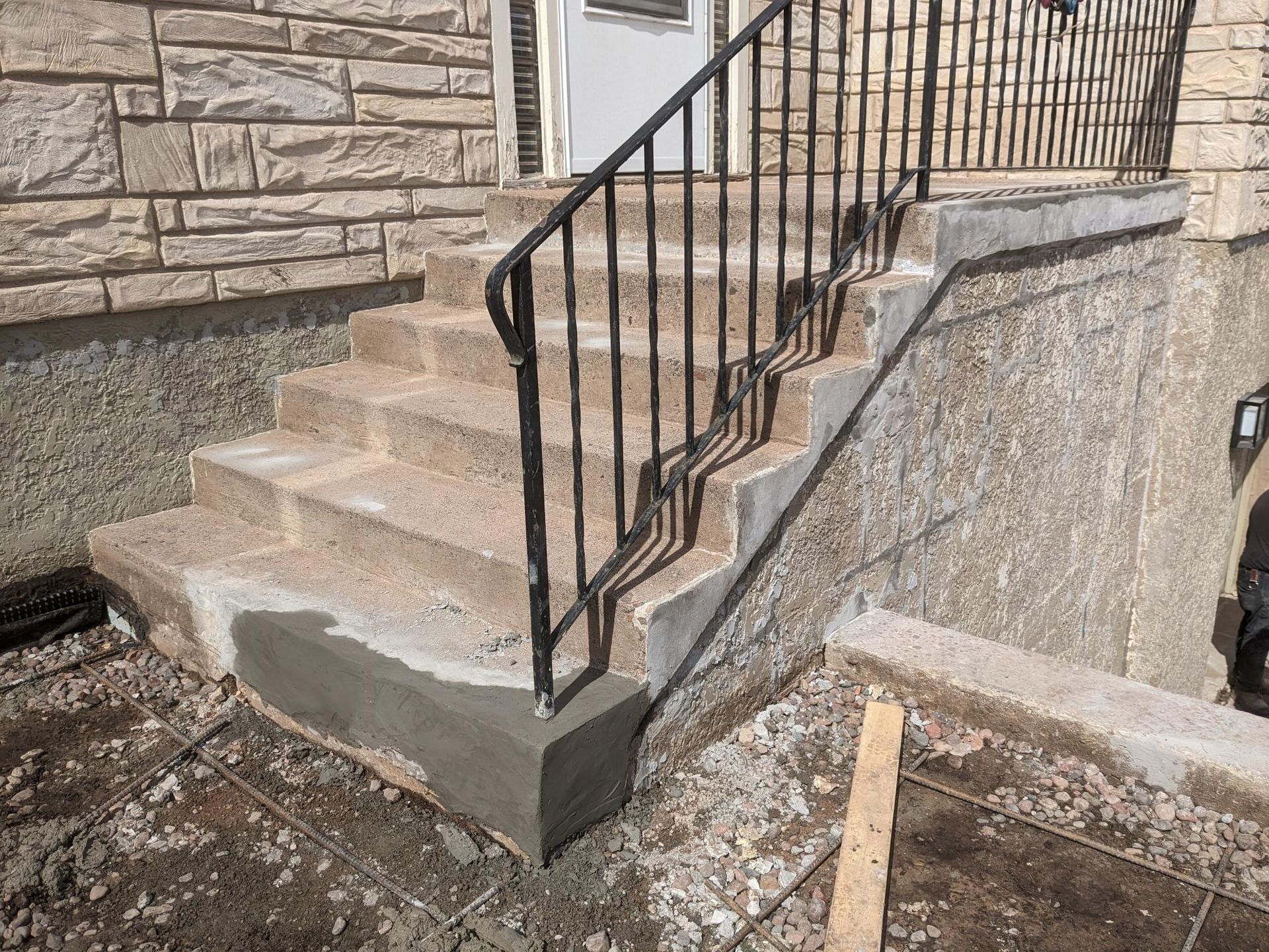 A set of stairs with a metal railing in front of a brick building.