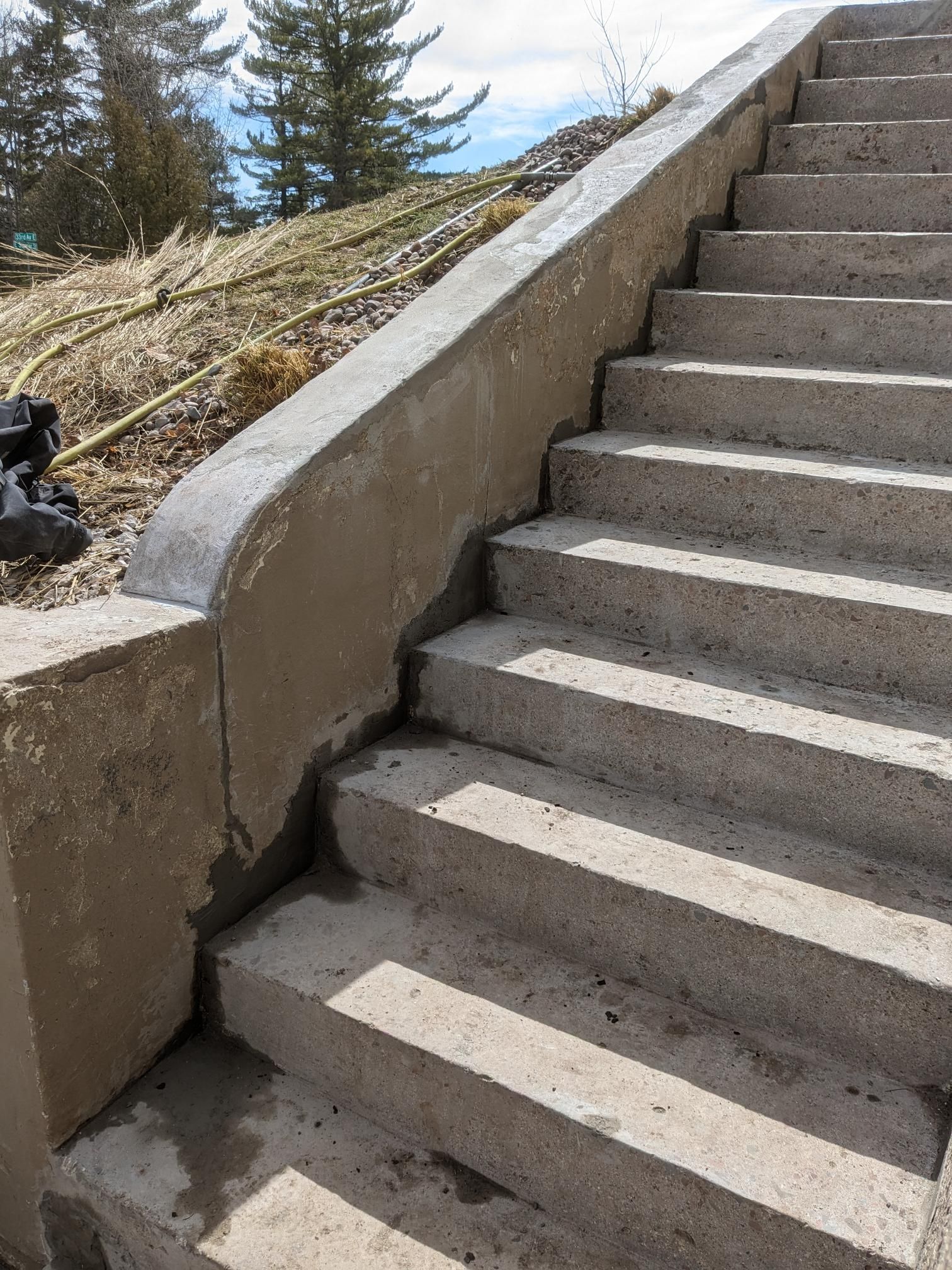 A set of concrete stairs leading up to a hill with trees in the background.