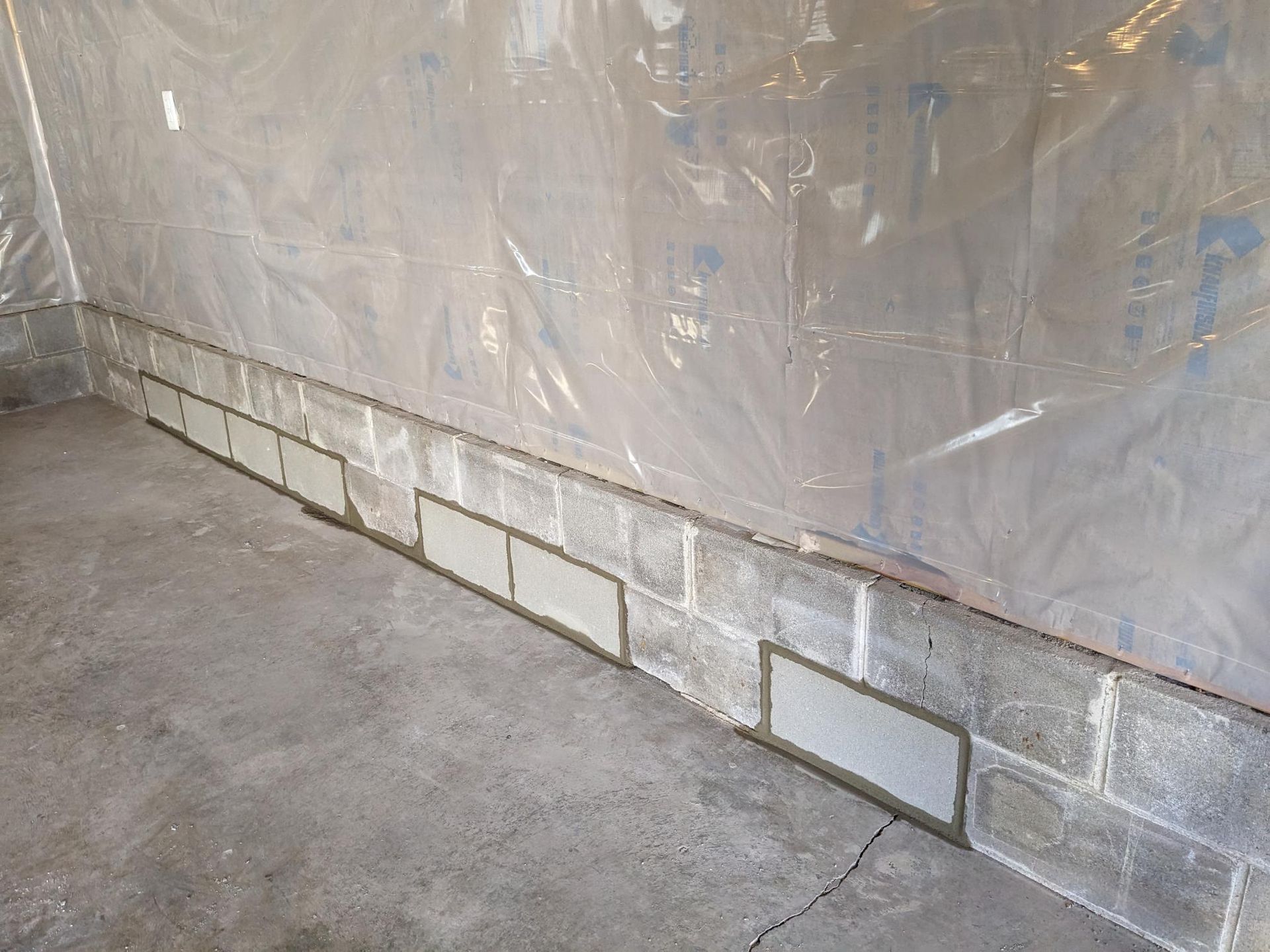 A room with a brick wall and a plastic sheet on the wall.