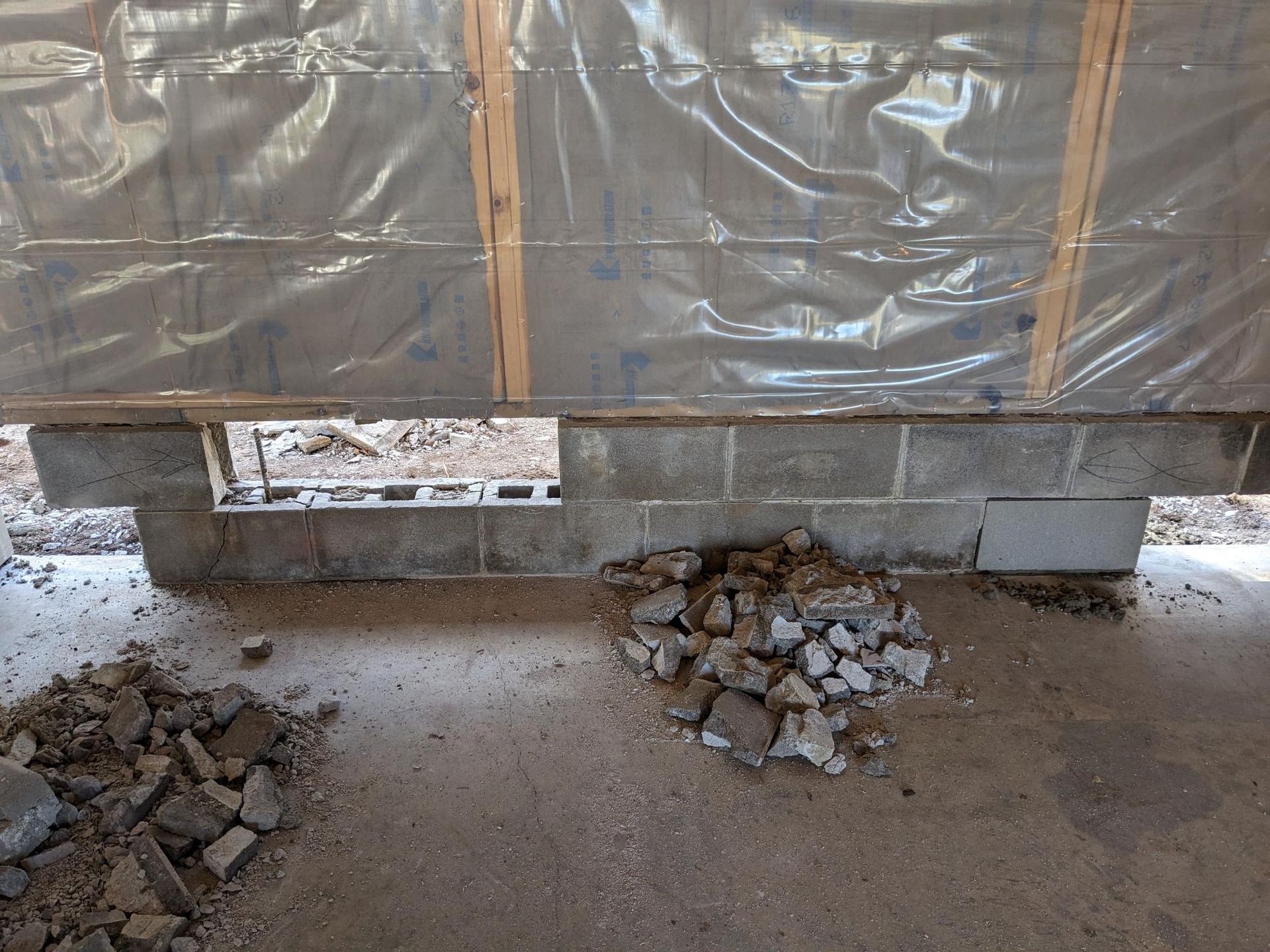 A pile of rocks is on the ground in front of a brick wall.