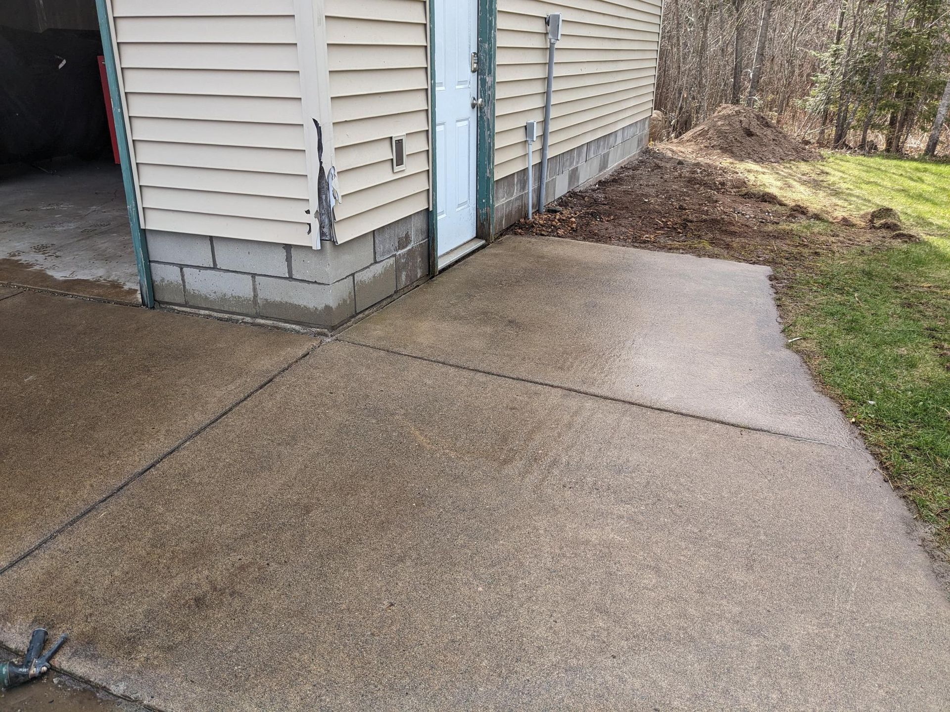 A concrete walkway leading to a garage next to a house.